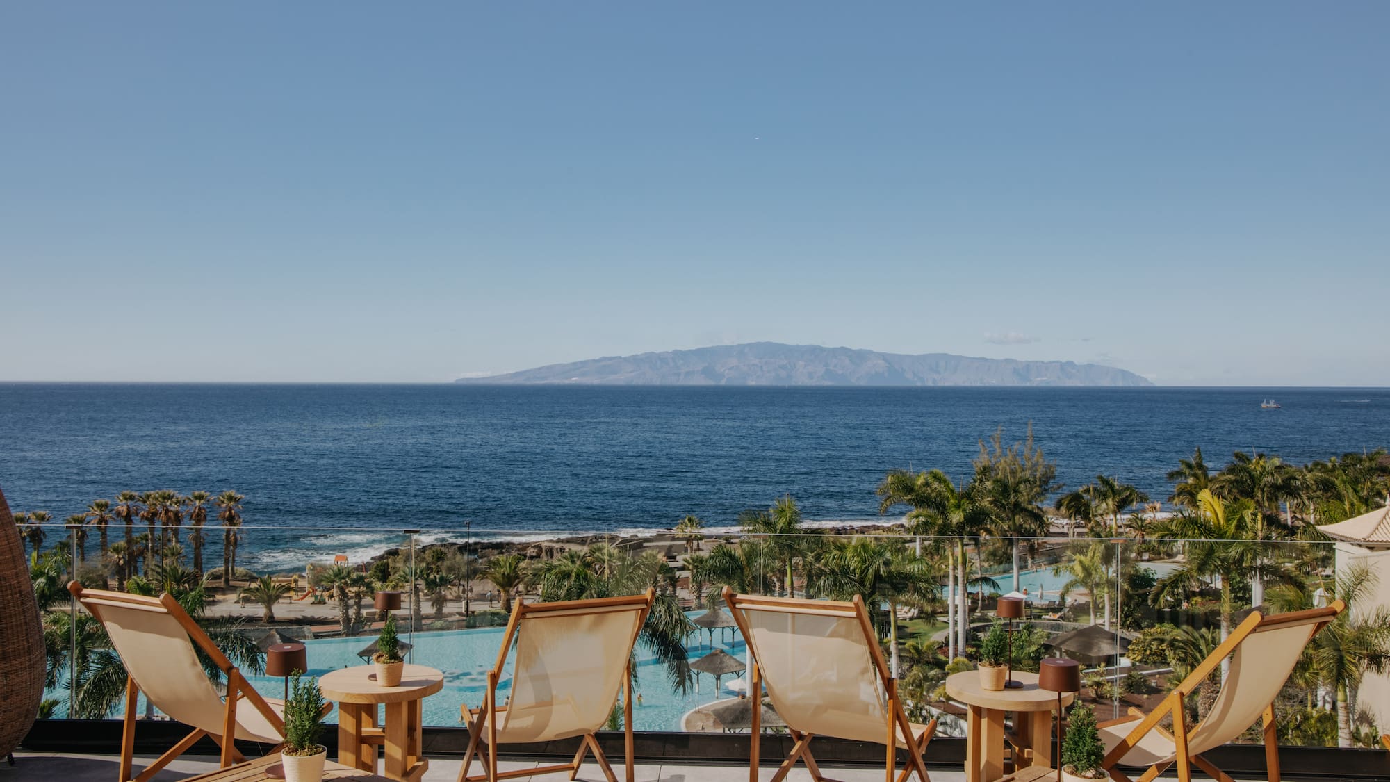 chairs and tables with chairs and a pool overlooking the ocean