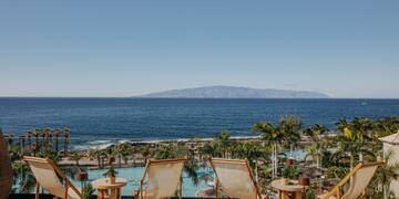 chairs and tables with chairs and a pool overlooking the ocean