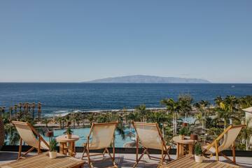 chairs and tables with chairs and a pool overlooking the ocean