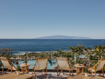 chairs and tables with chairs and a pool overlooking the ocean