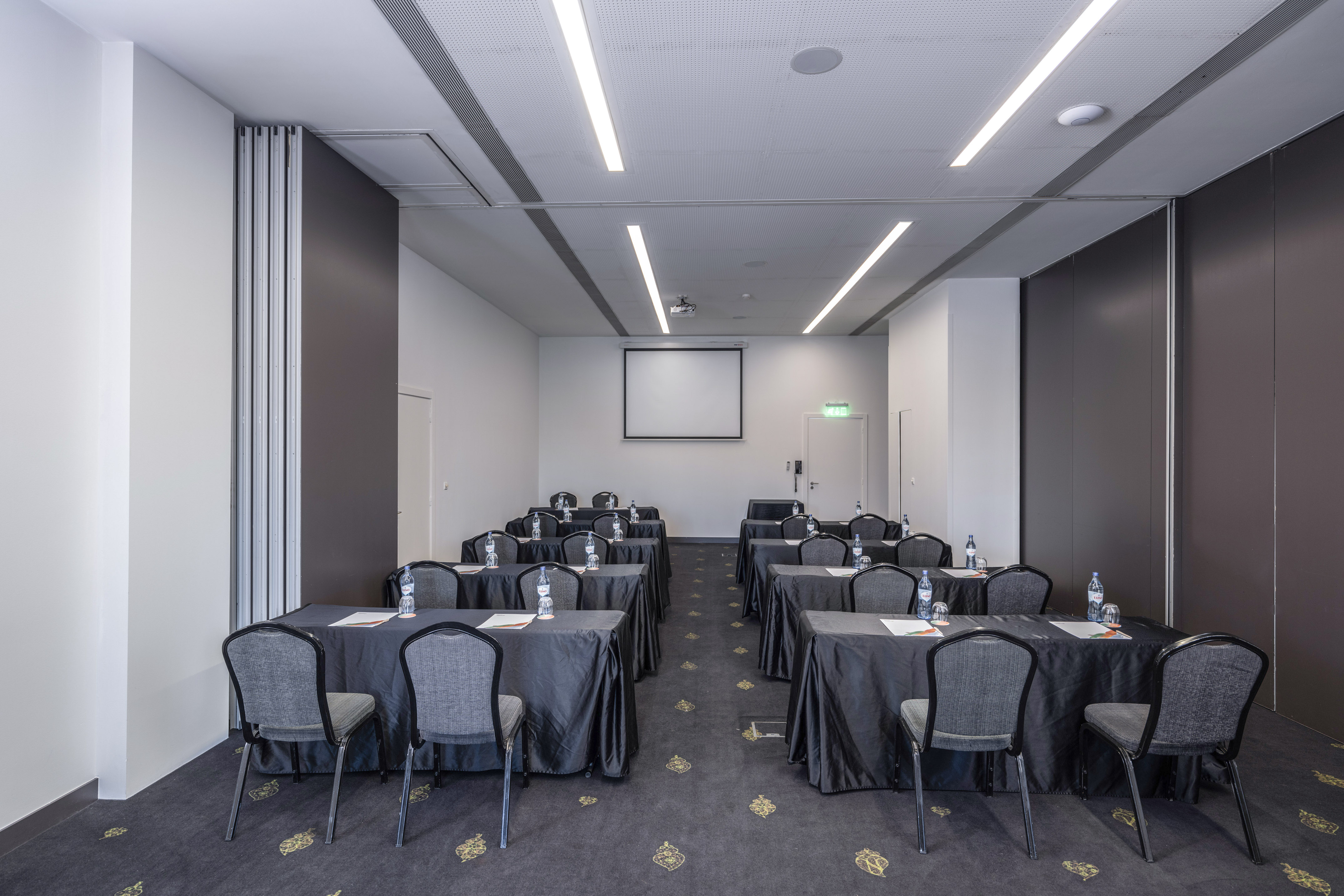 Modern conference room with projector screen, tables, chairs, movable walls.