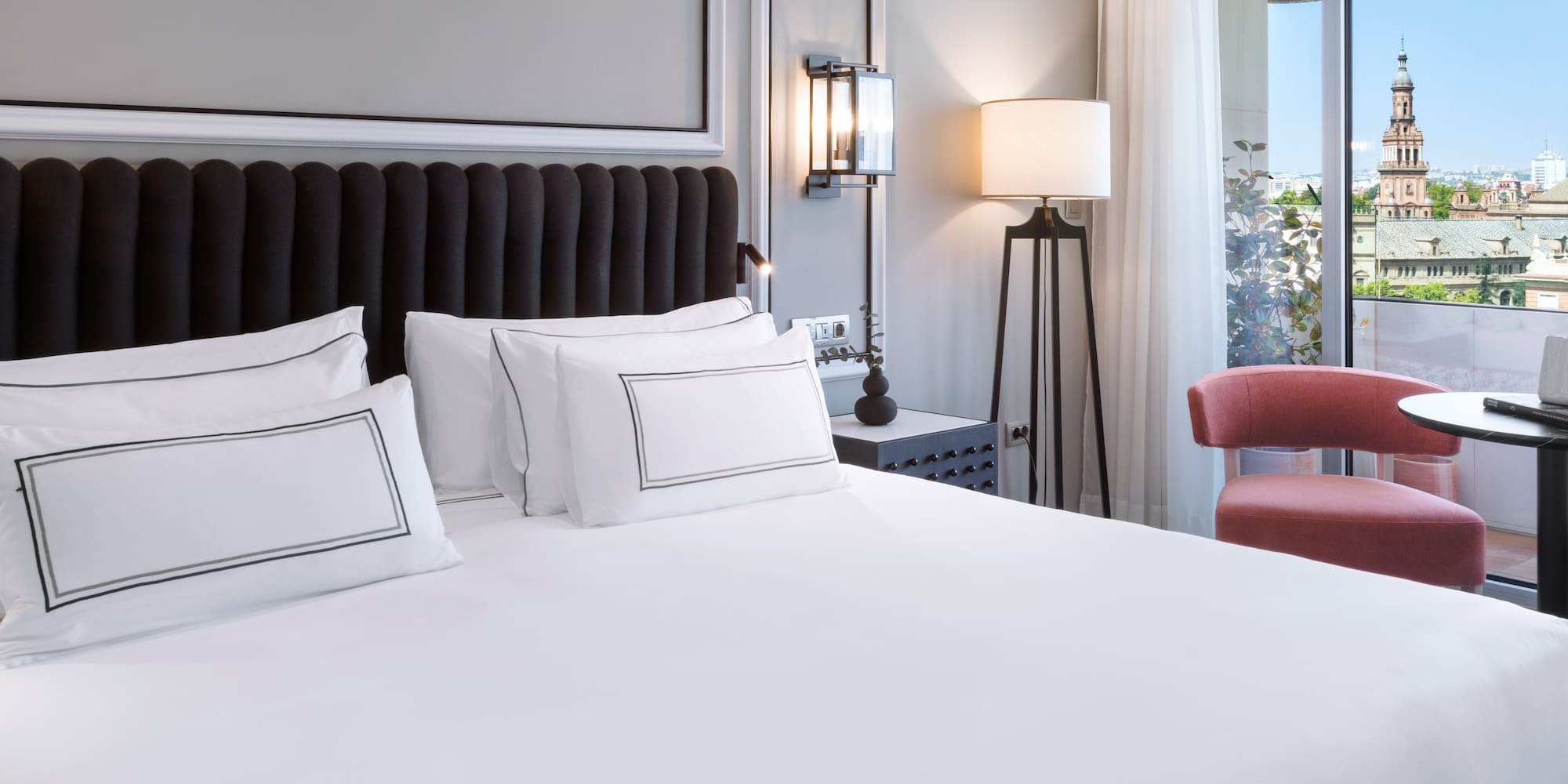 a bed with white sheets and a red chair