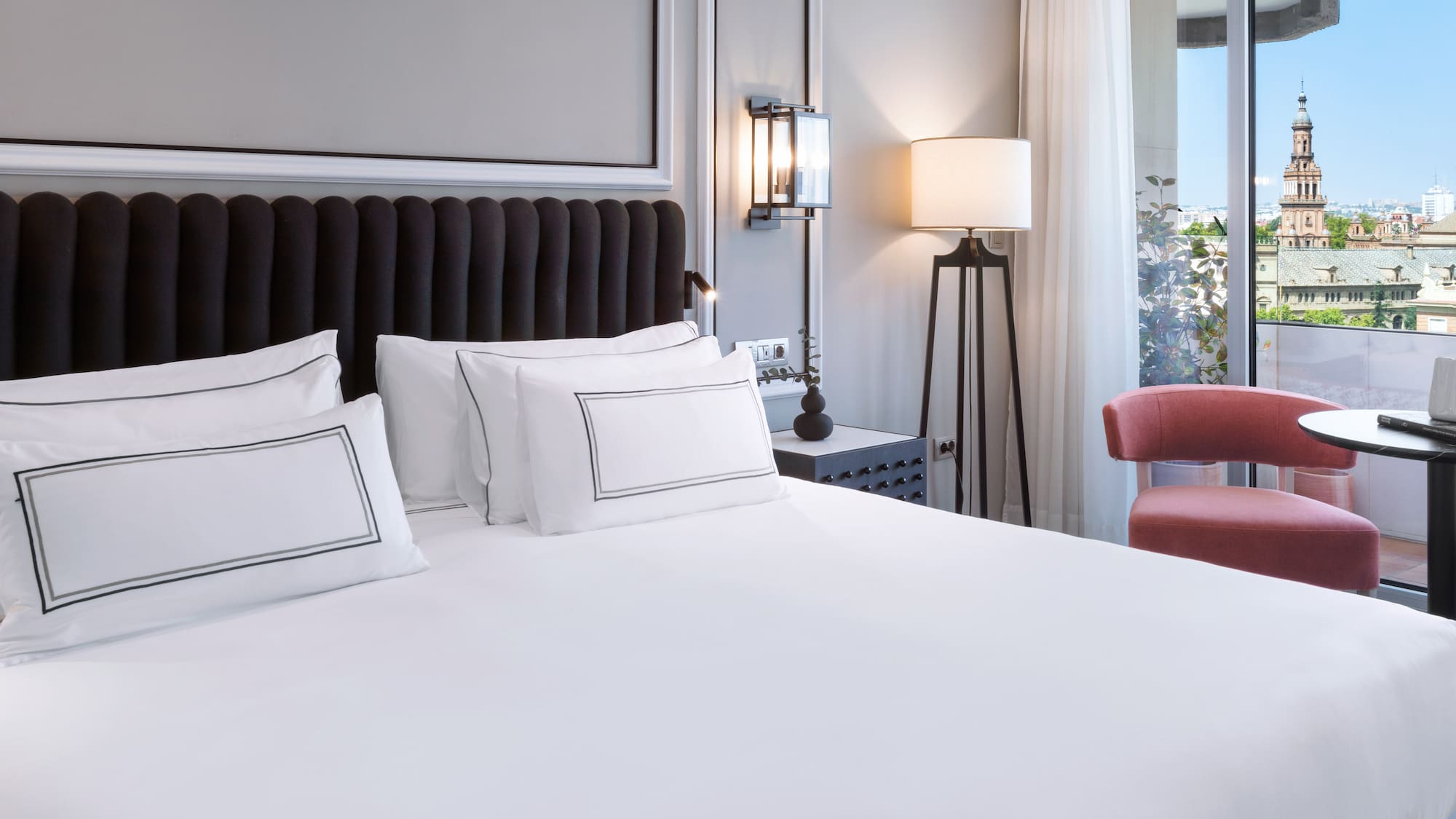 a bed with white sheets and a red chair