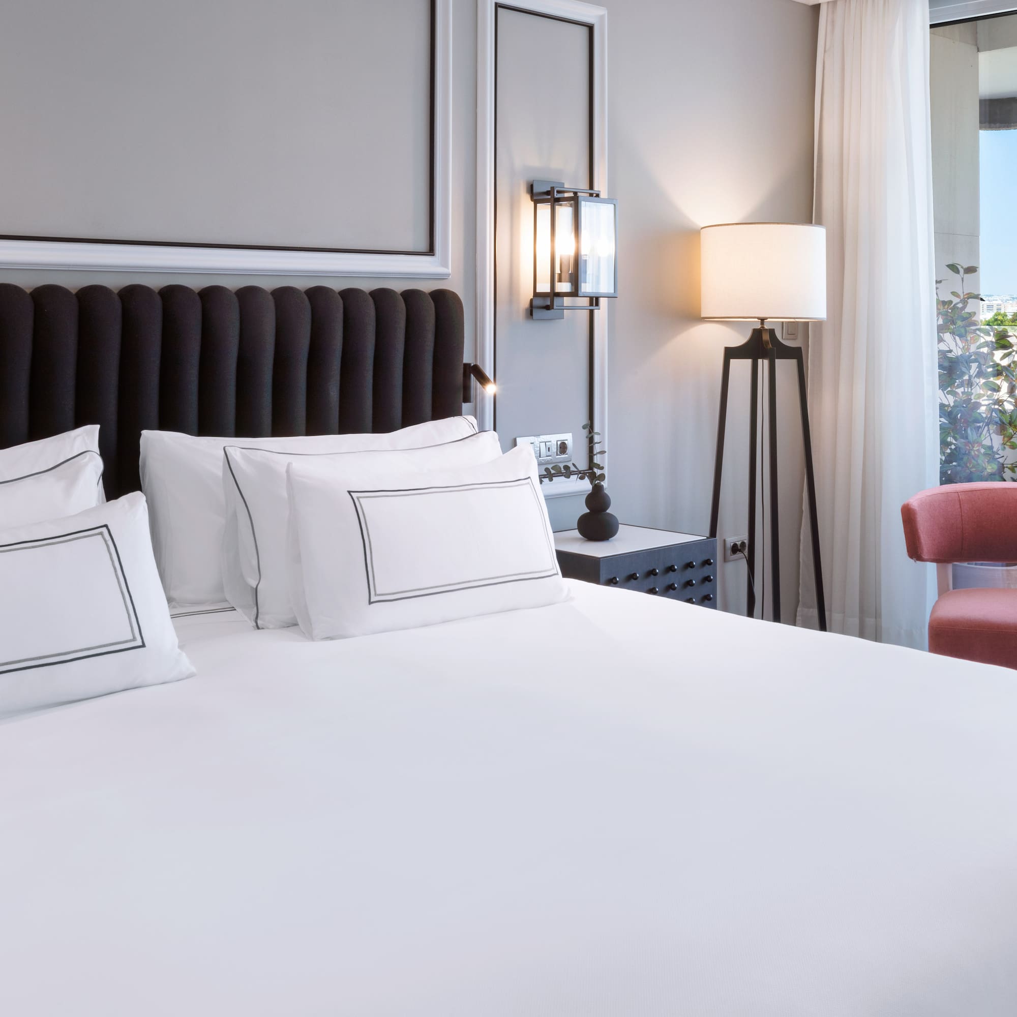 a bed with white sheets and a red chair