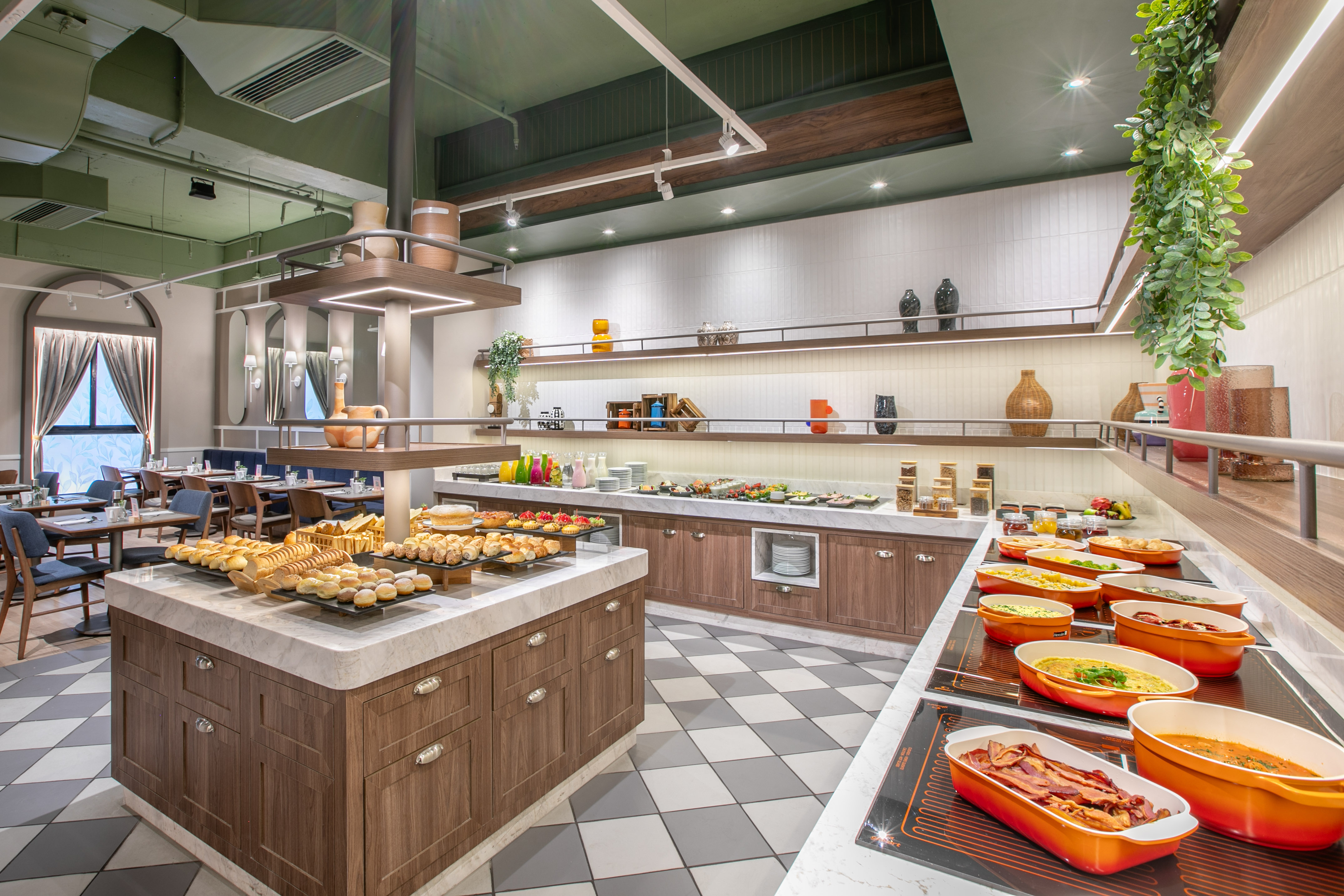 Modern restaurant buffet with hot breakfast, fresh pastries, and dining area.