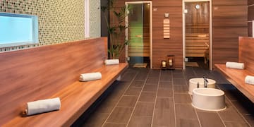 a room with a bench and sink and towels