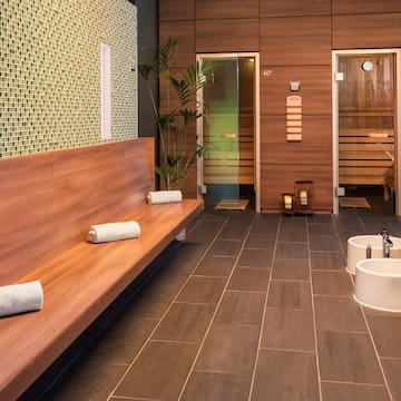 a room with a bench and sink and towels