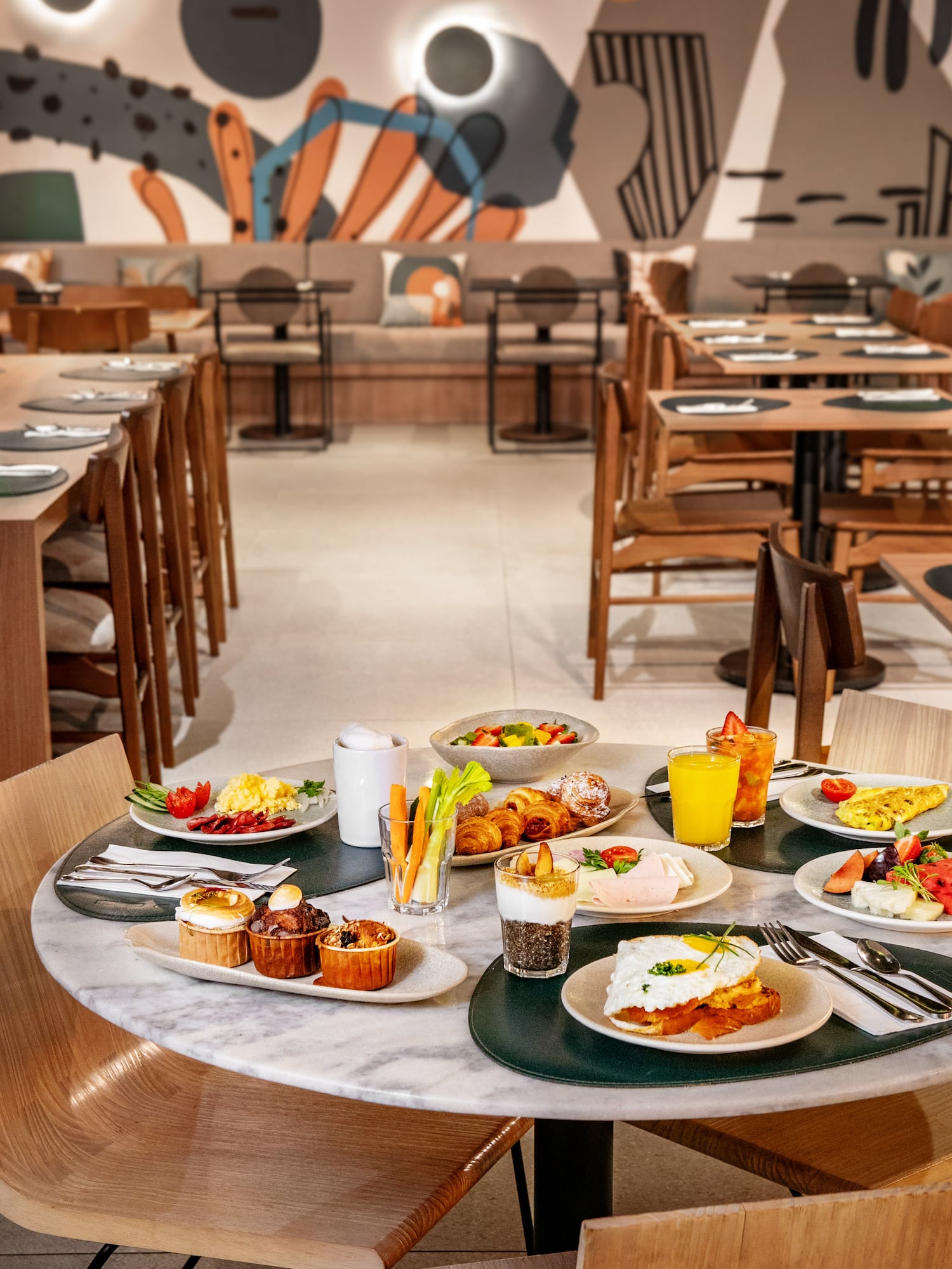 Breakfast spread with eggs, fruit, pastries, and juice in a modern restaurant.