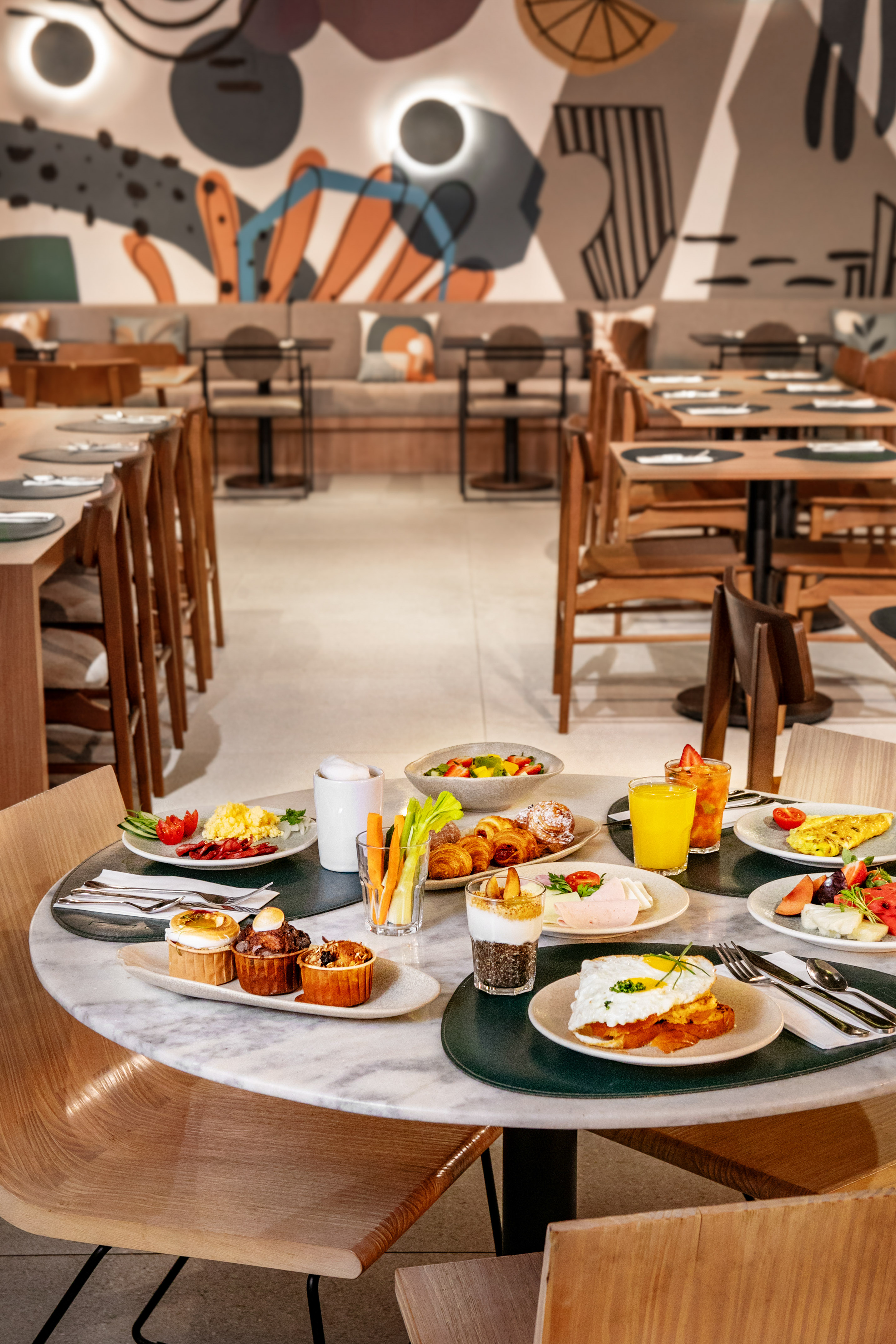 Breakfast spread with eggs, fruit, pastries, and juice in a modern restaurant.