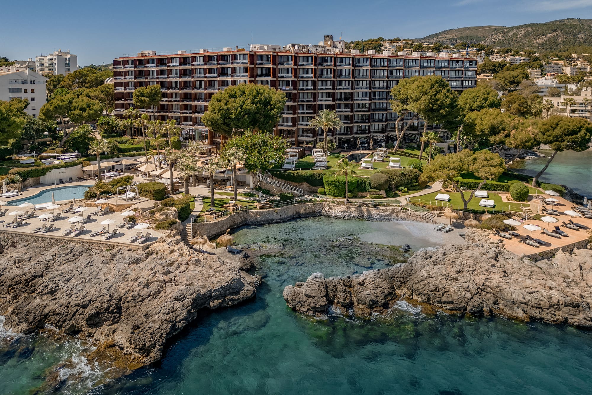 Luxury coastal resort hotel with pools, private beach, and clear sea.