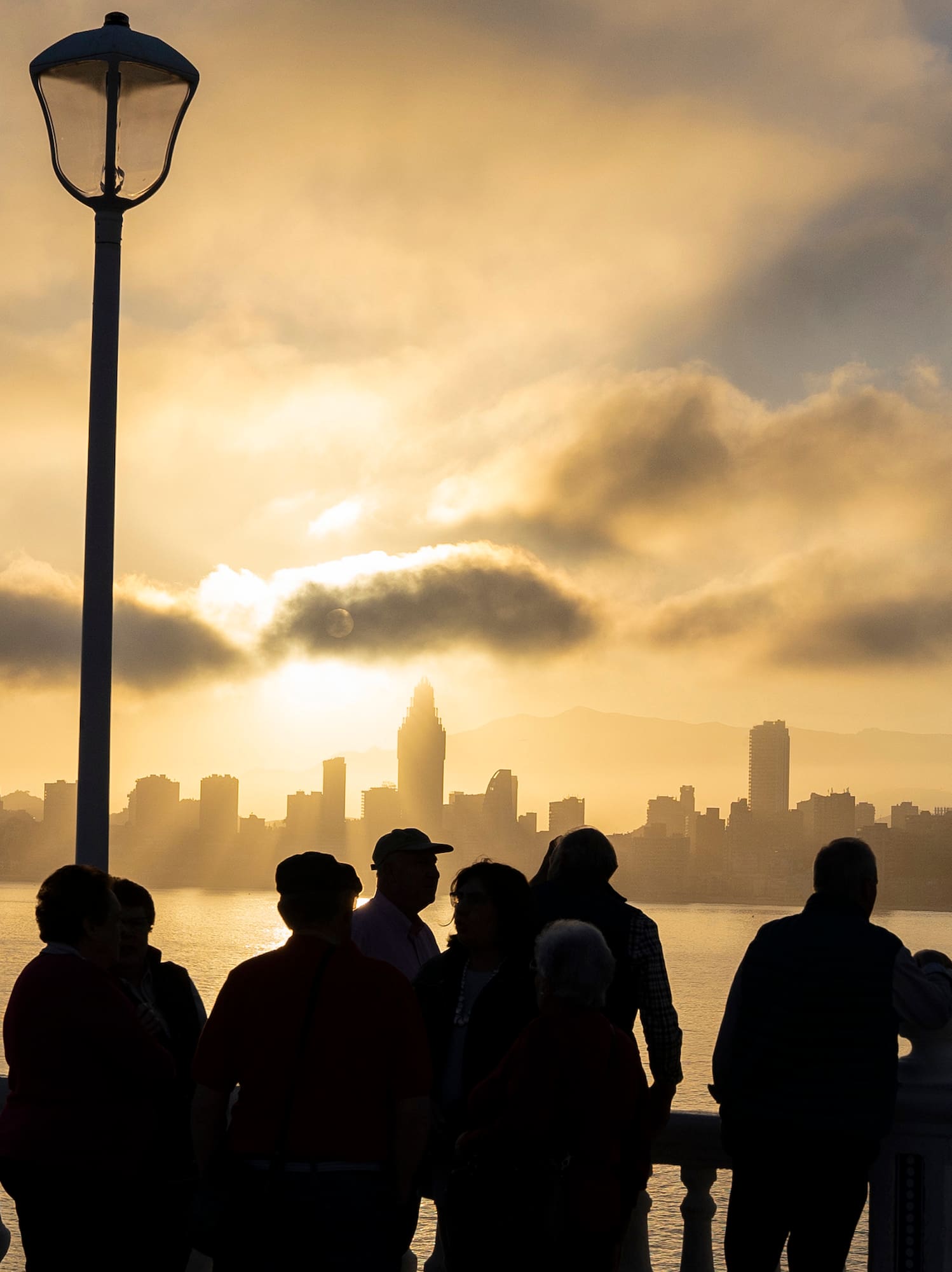 a group of people standing on a railing overlooking a body of water