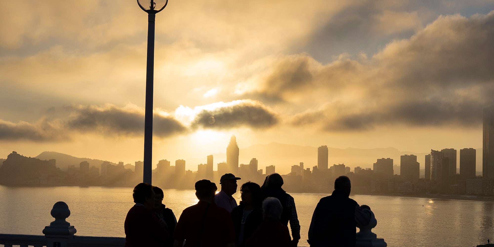 a group of people standing on a railing overlooking a body of water