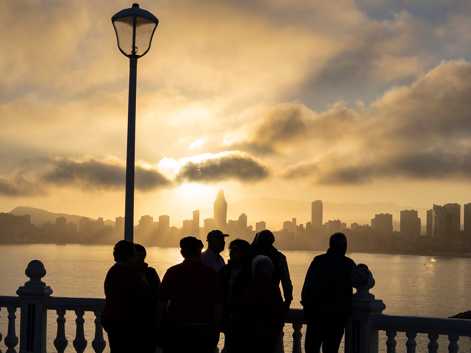 a group of people standing on a railing overlooking a body of water