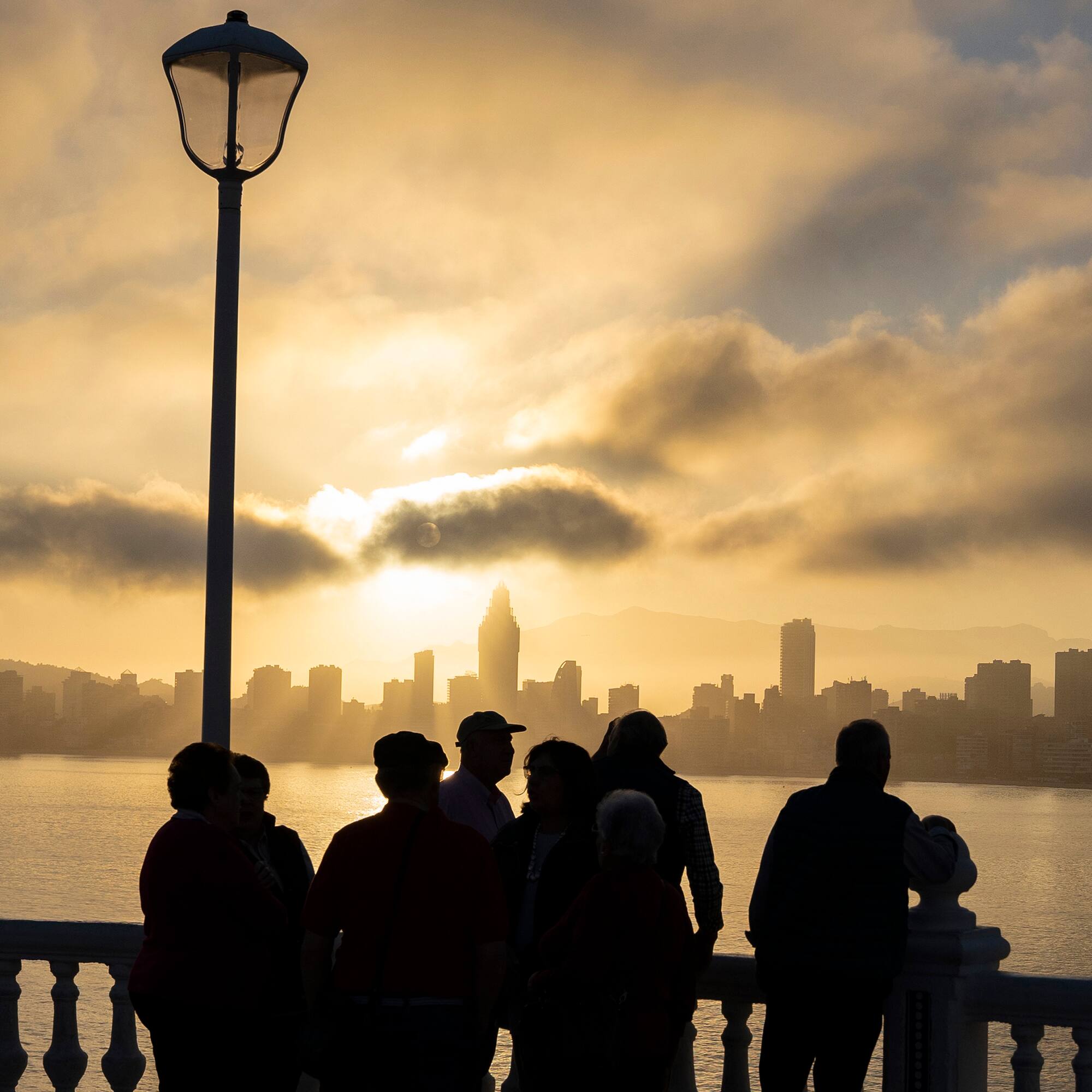 a group of people standing on a railing overlooking a body of water