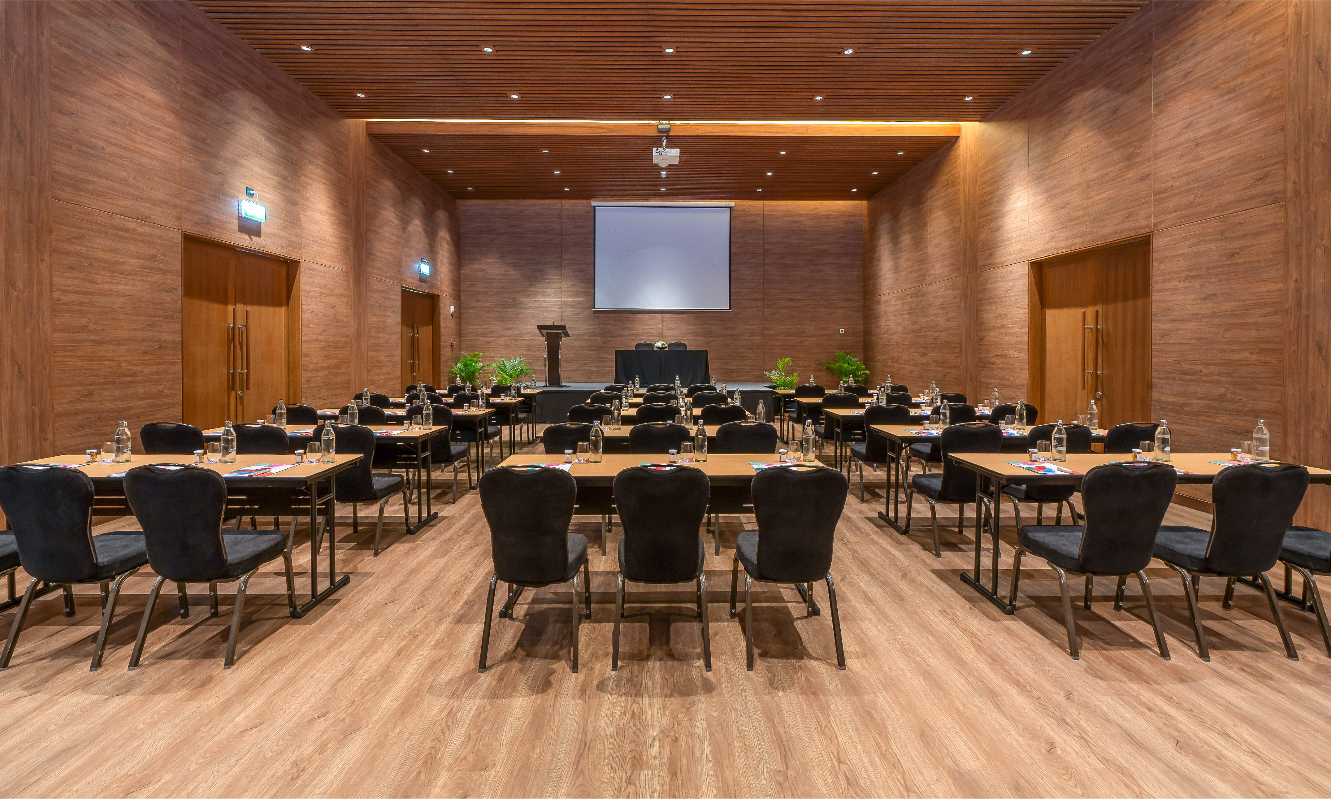 Modern wooden conference room setup for meetings, with projector and tables.