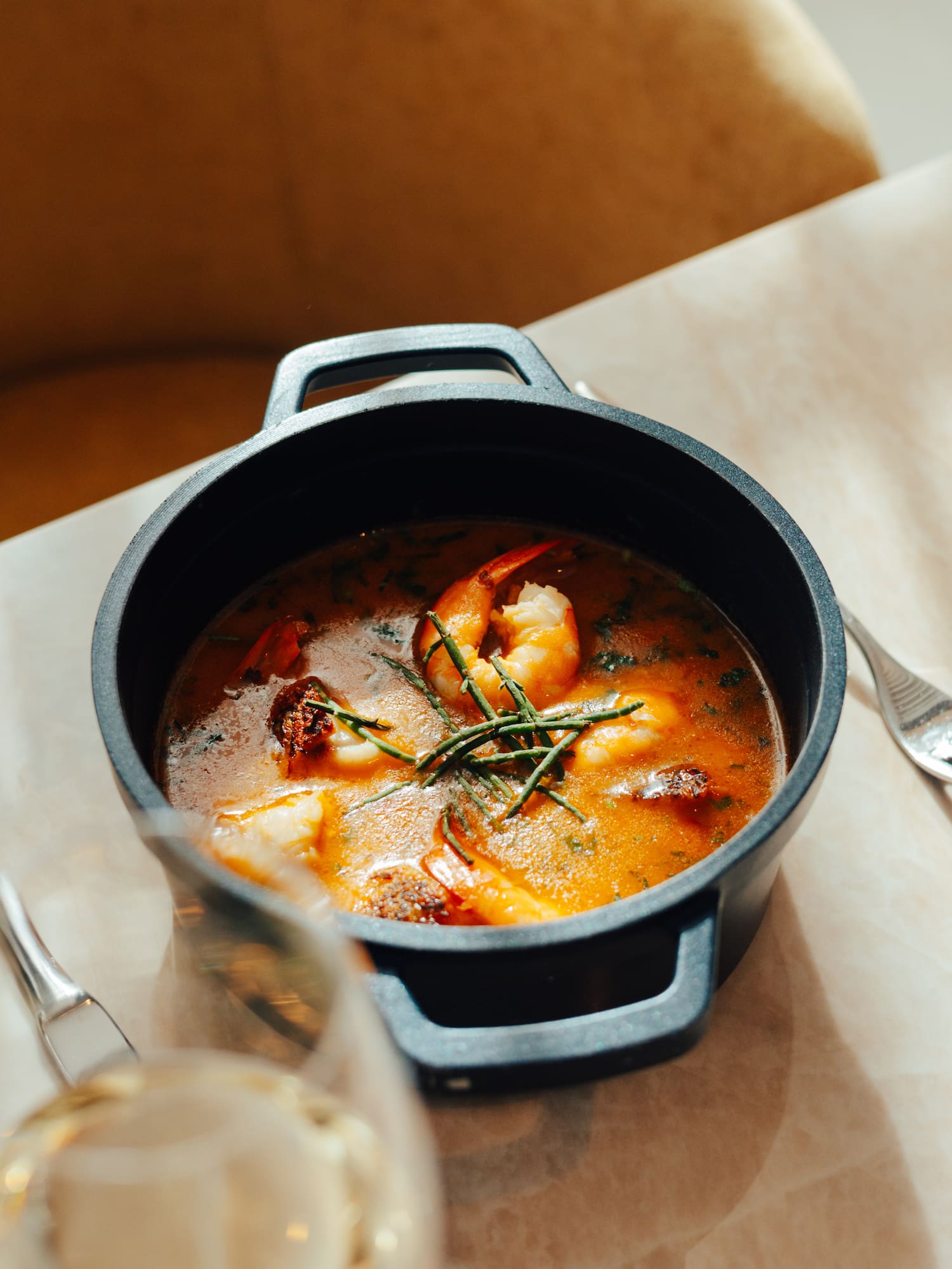 Shrimp and seafood stew in a black pot, garnished with fresh herbs.