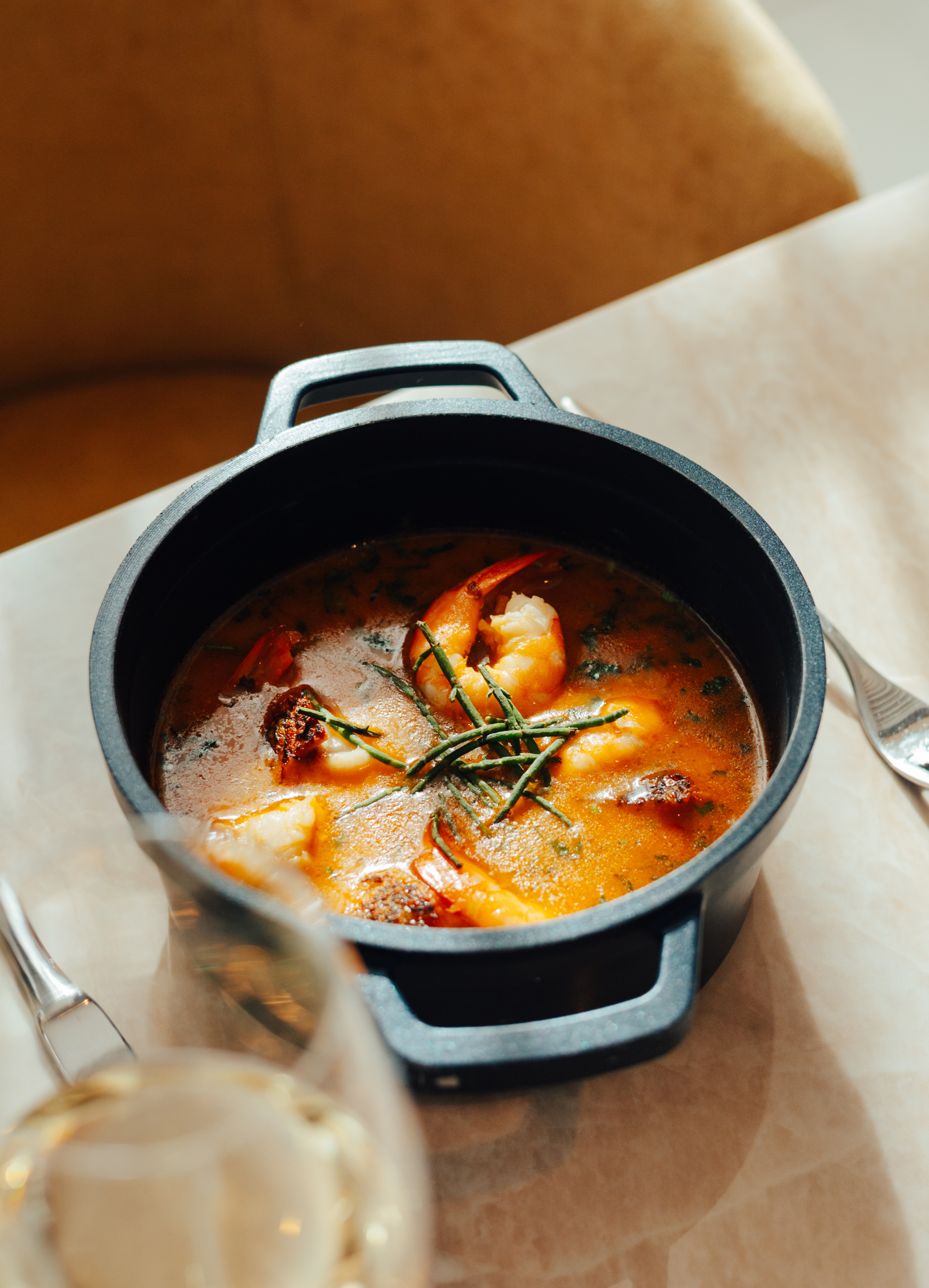 Shrimp and seafood stew in a black pot, garnished with fresh herbs.