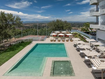 a pool with chairs and umbrellas on a patio