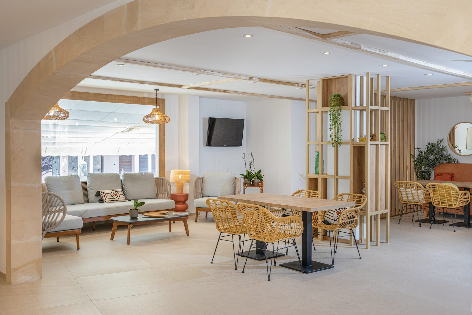 Modern hotel lobby with lounge seating and dining area featuring rattan chairs.
