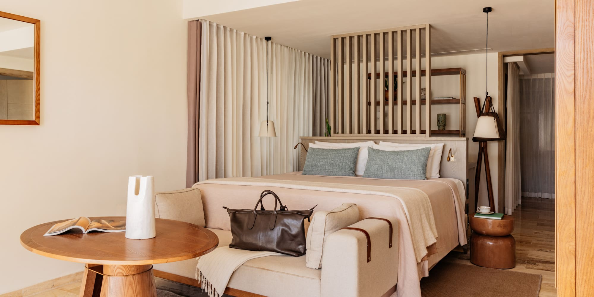 Modern luxury hotel bedroom with king bed, sofa, and wood accents.