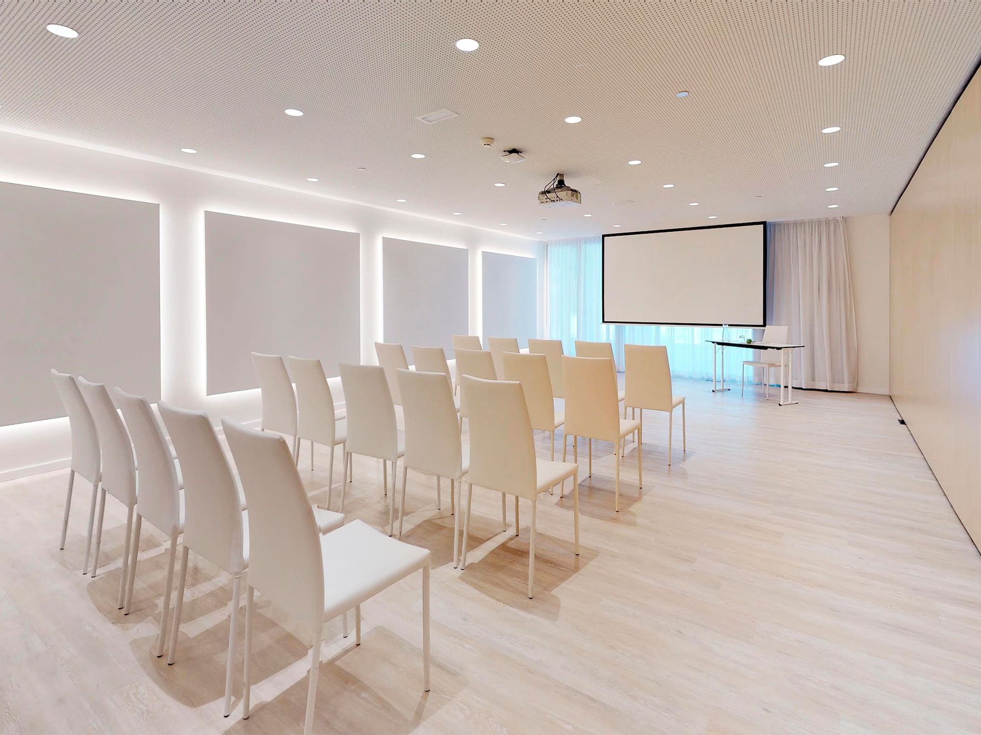 a room with white chairs and a projector screen