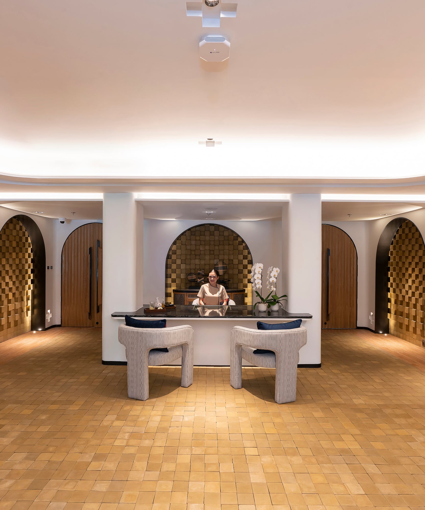 Luxury hotel reception desk with staff, modern arches, and warm lighting.