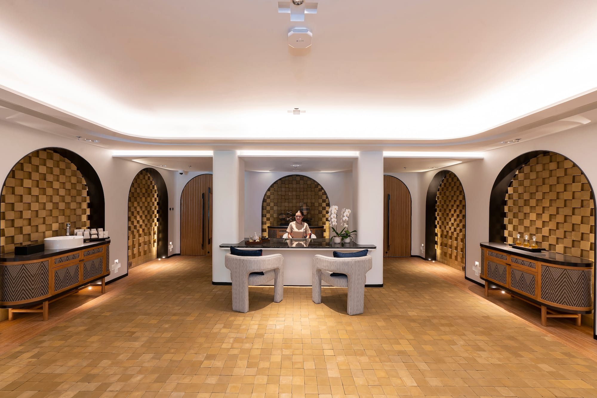 Luxury hotel reception desk with staff, modern arches, and warm lighting.