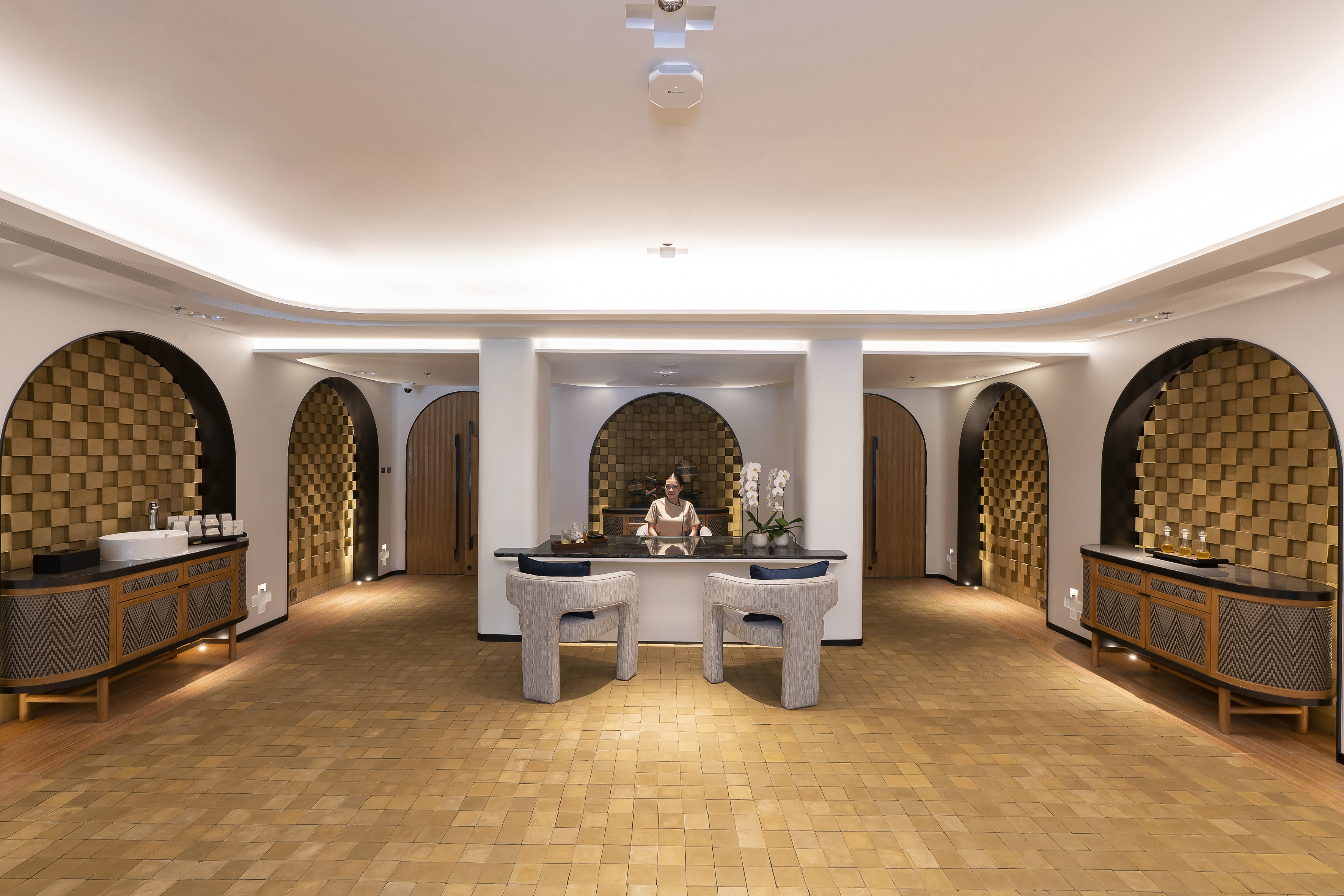 Luxury hotel reception desk with staff, modern arches, and warm lighting.
