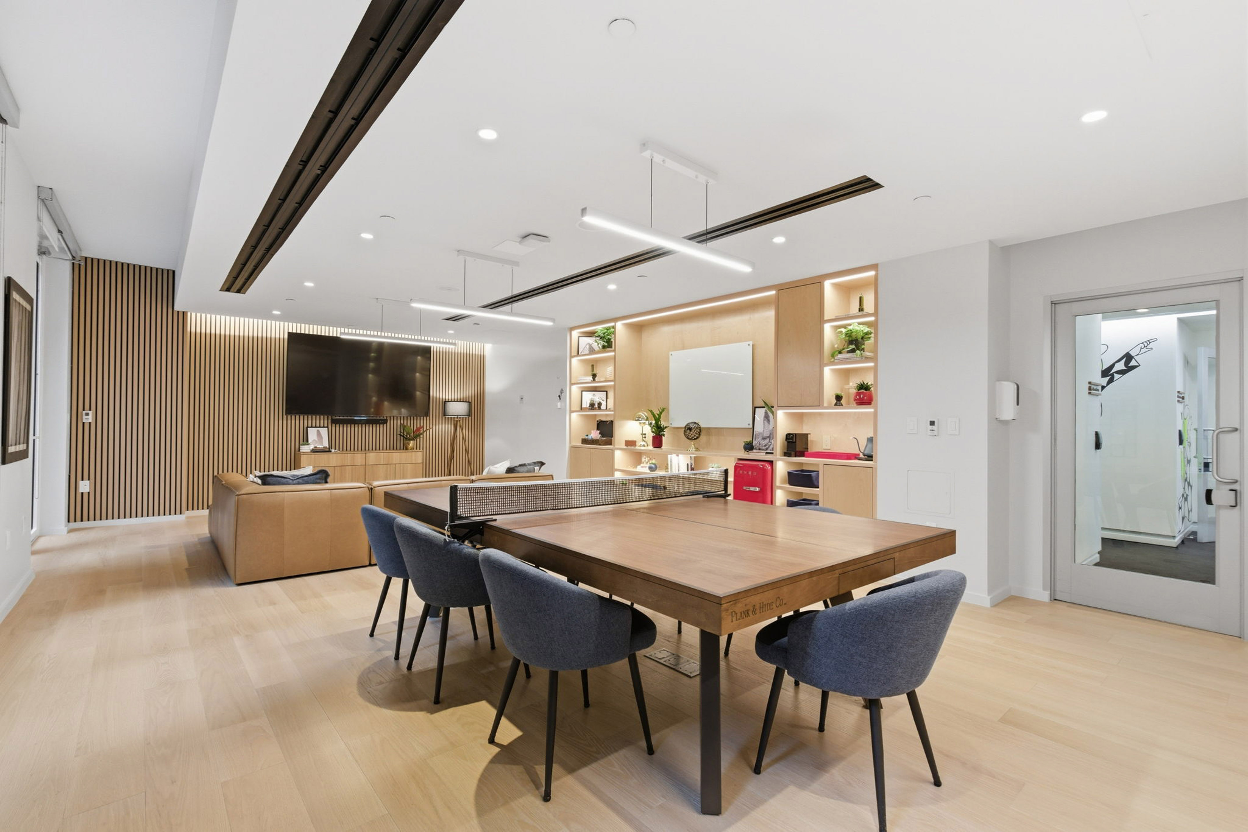 Contemporary office lounge with a ping-pong table, sofa, and wood accents.