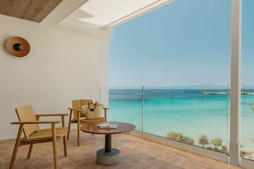 a balcony with a table and chairs and a beach view