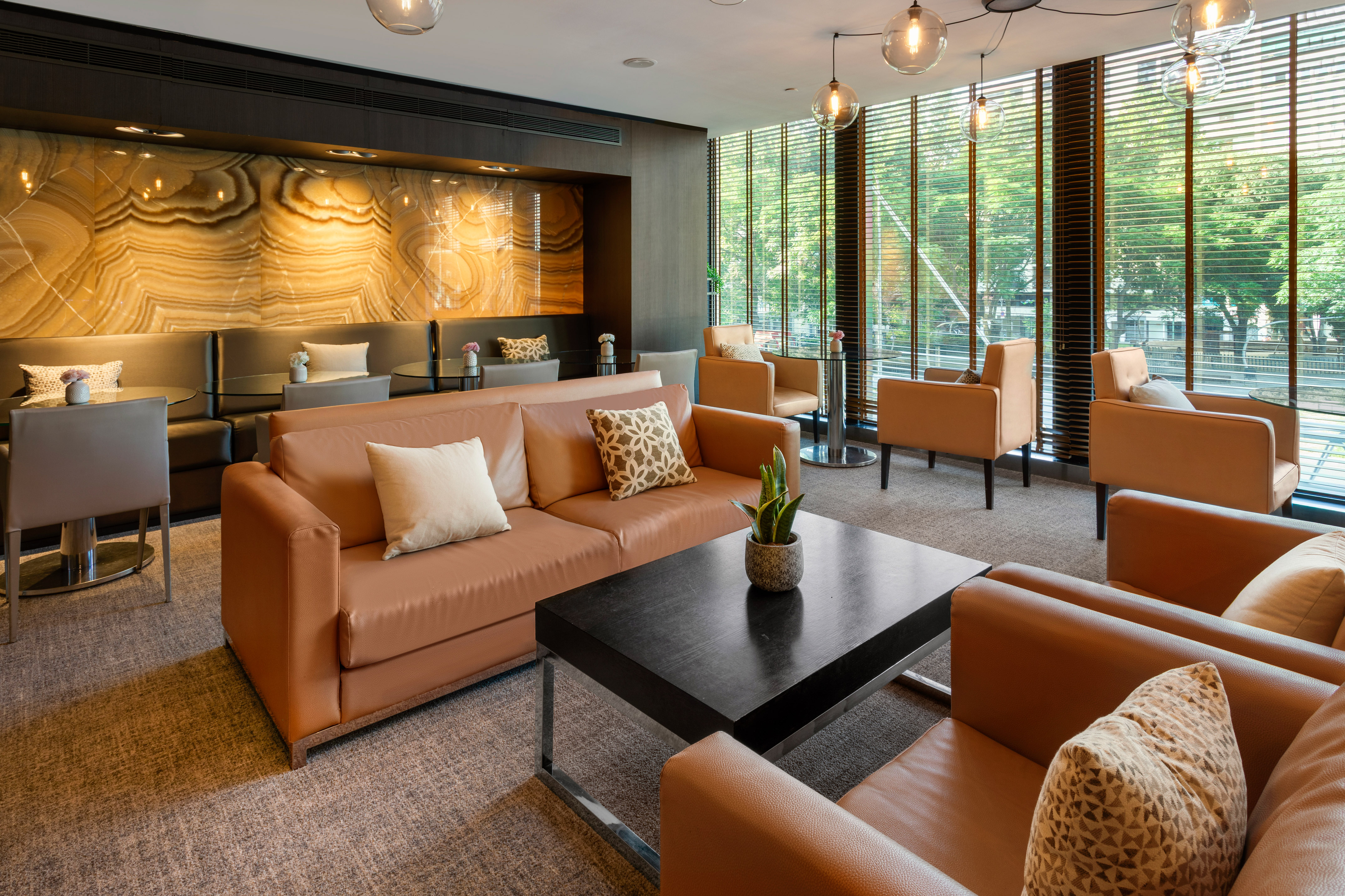 Modern hotel lounge with brown leather seating and illuminated onyx wall.