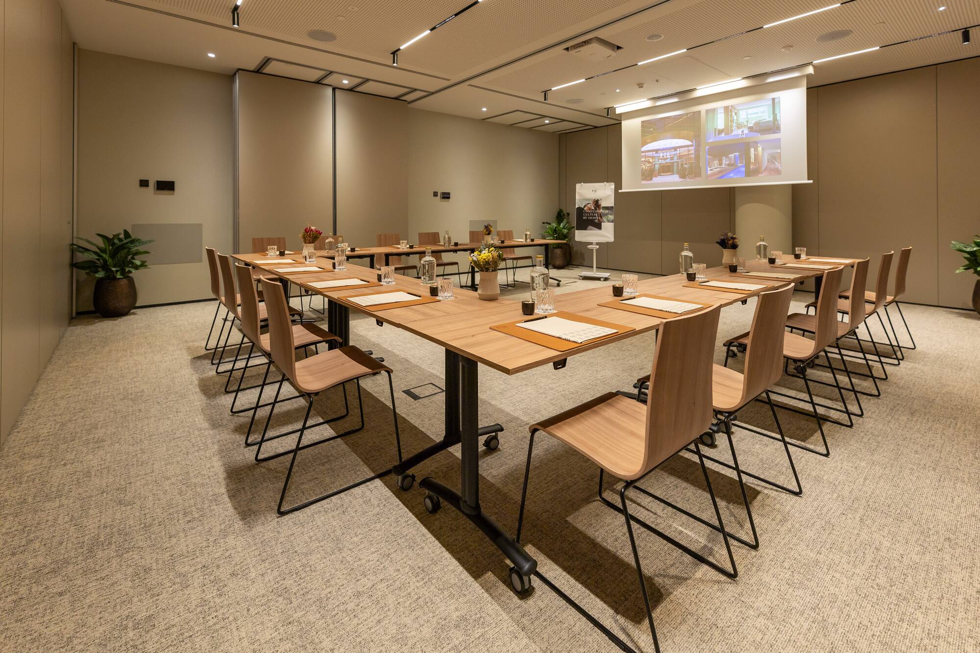 Modern conference room with U-shaped table, ergonomic chairs, and projection screen.