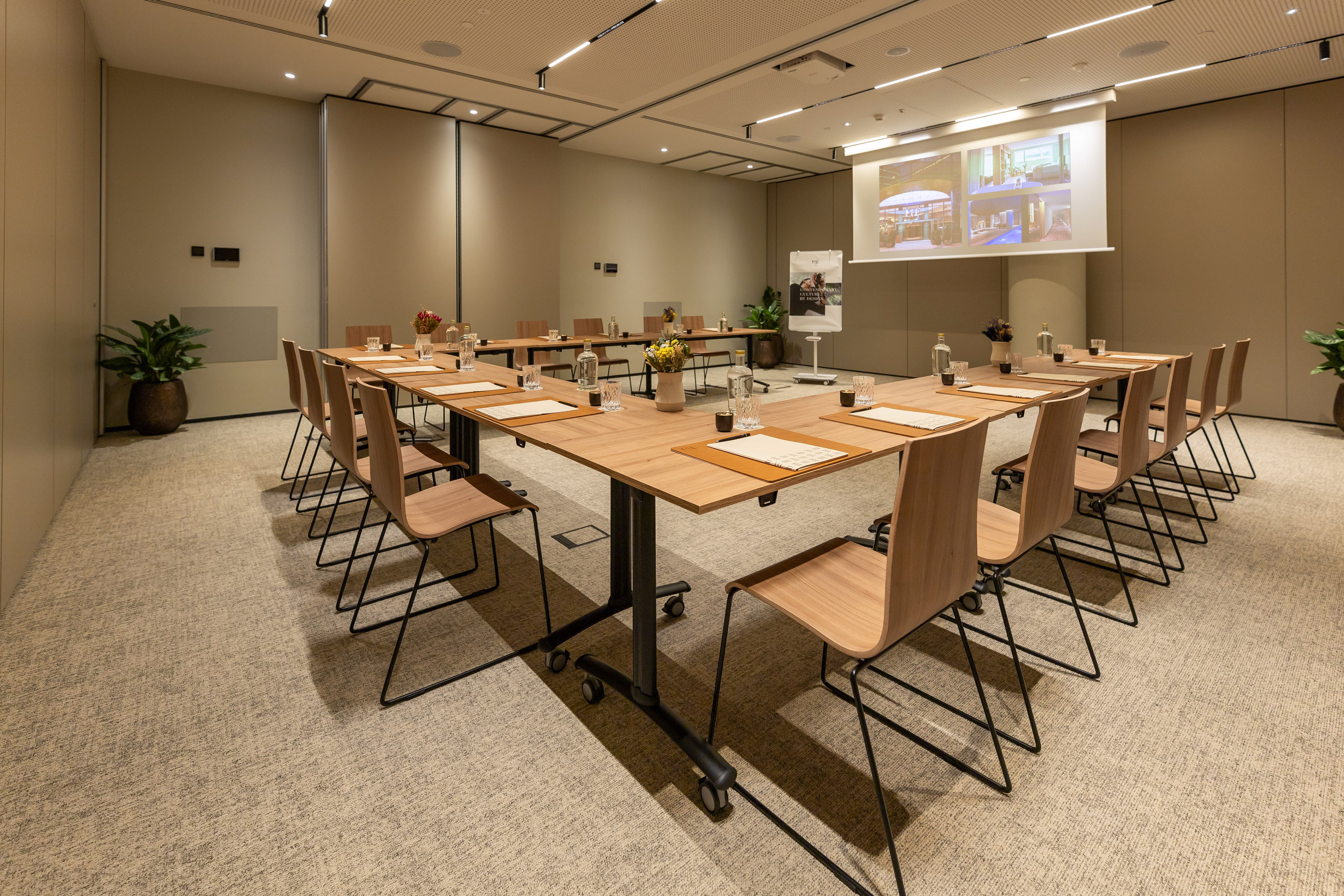 Modern conference room with U-shaped table, ergonomic chairs, and projection screen.