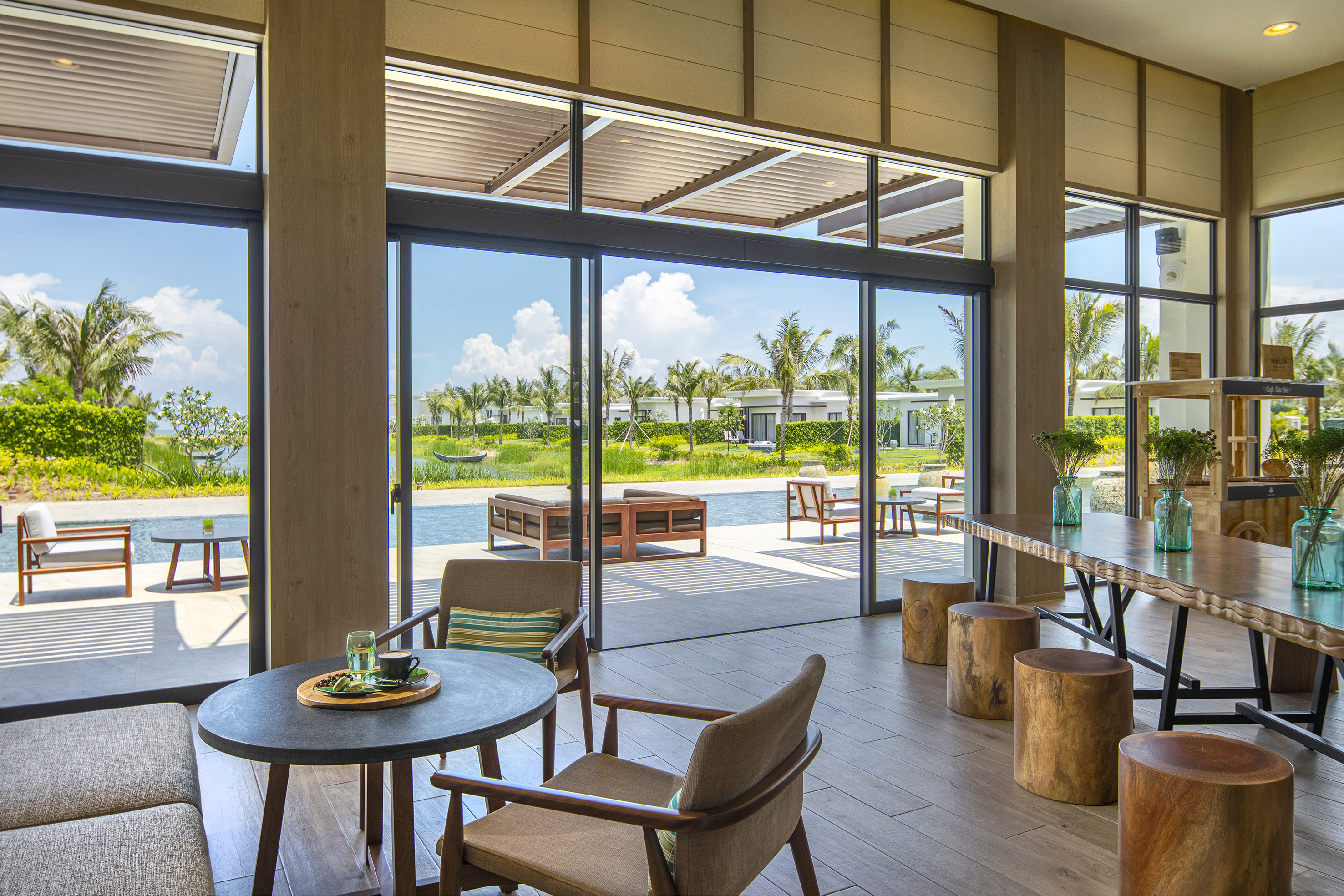Stylish resort lounge with coffee, modern decor, and panoramic tropical views.