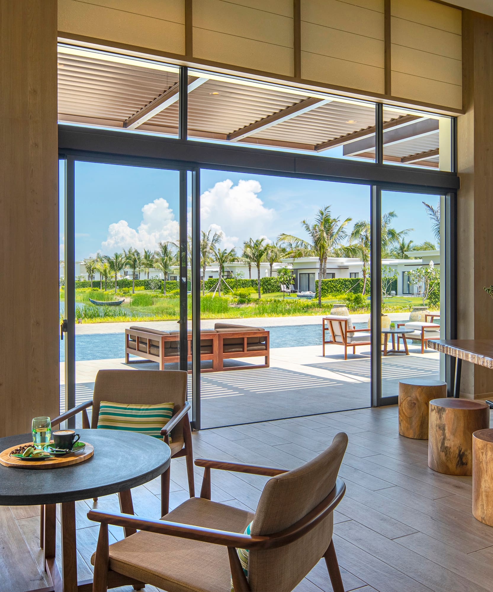 Stylish resort lounge with coffee, modern decor, and panoramic tropical views.