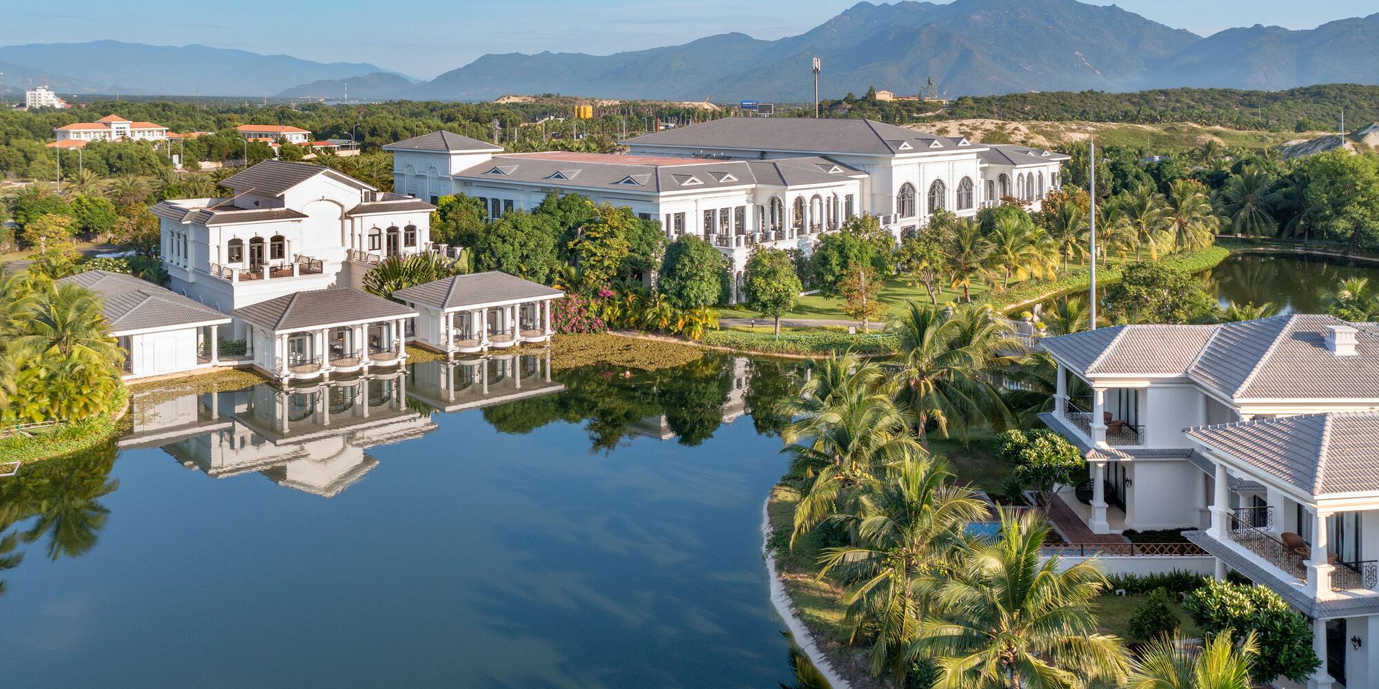 a large white building surrounded by trees and water