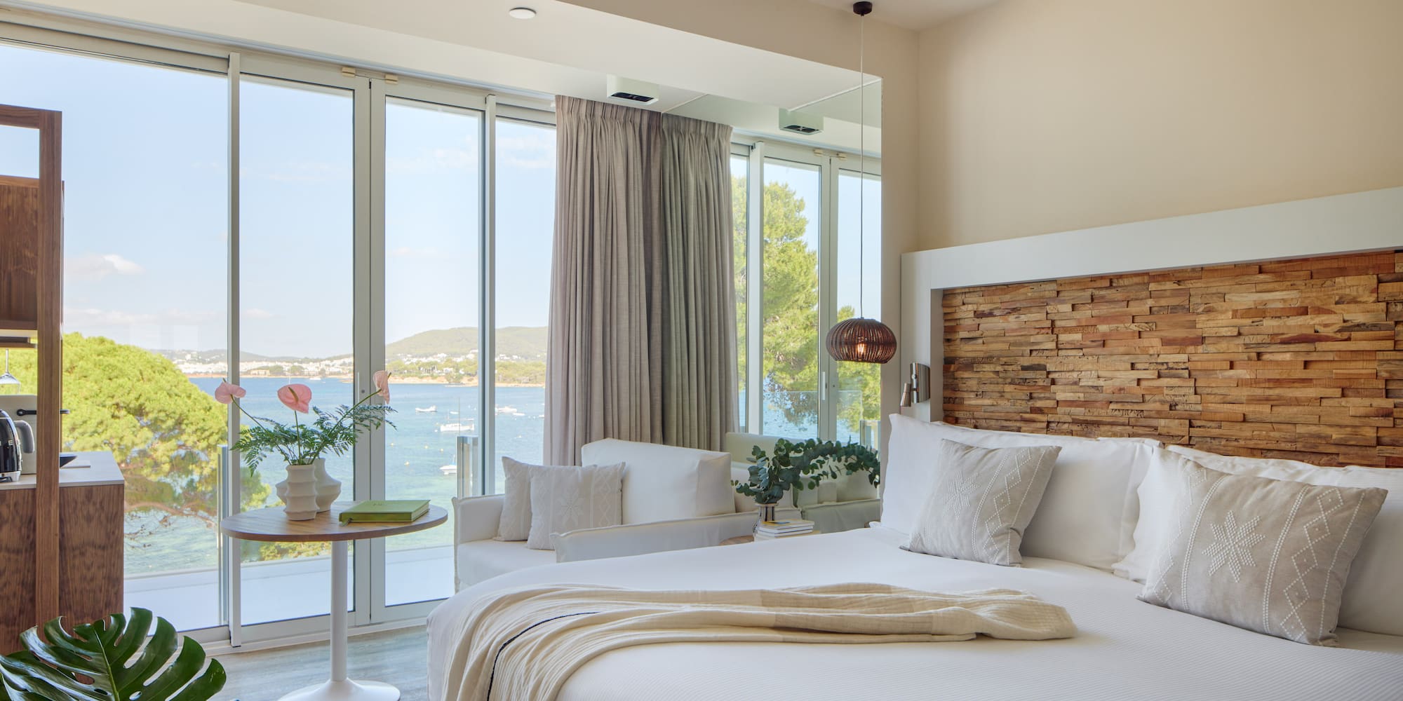 Modern hotel bedroom with bay view windows, king bed, and wood headboard.