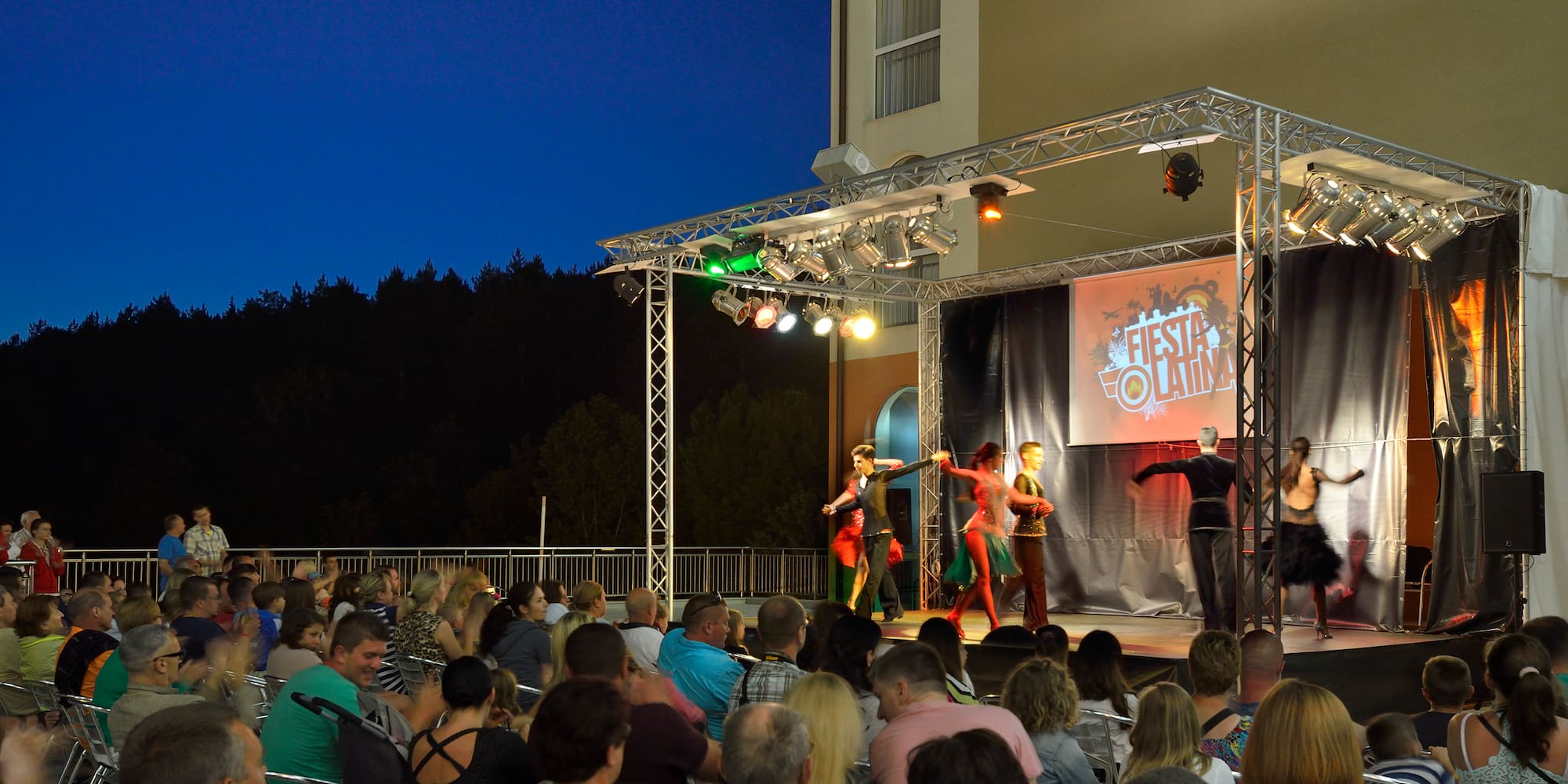 a group of people performing on a stage with a crowd watching