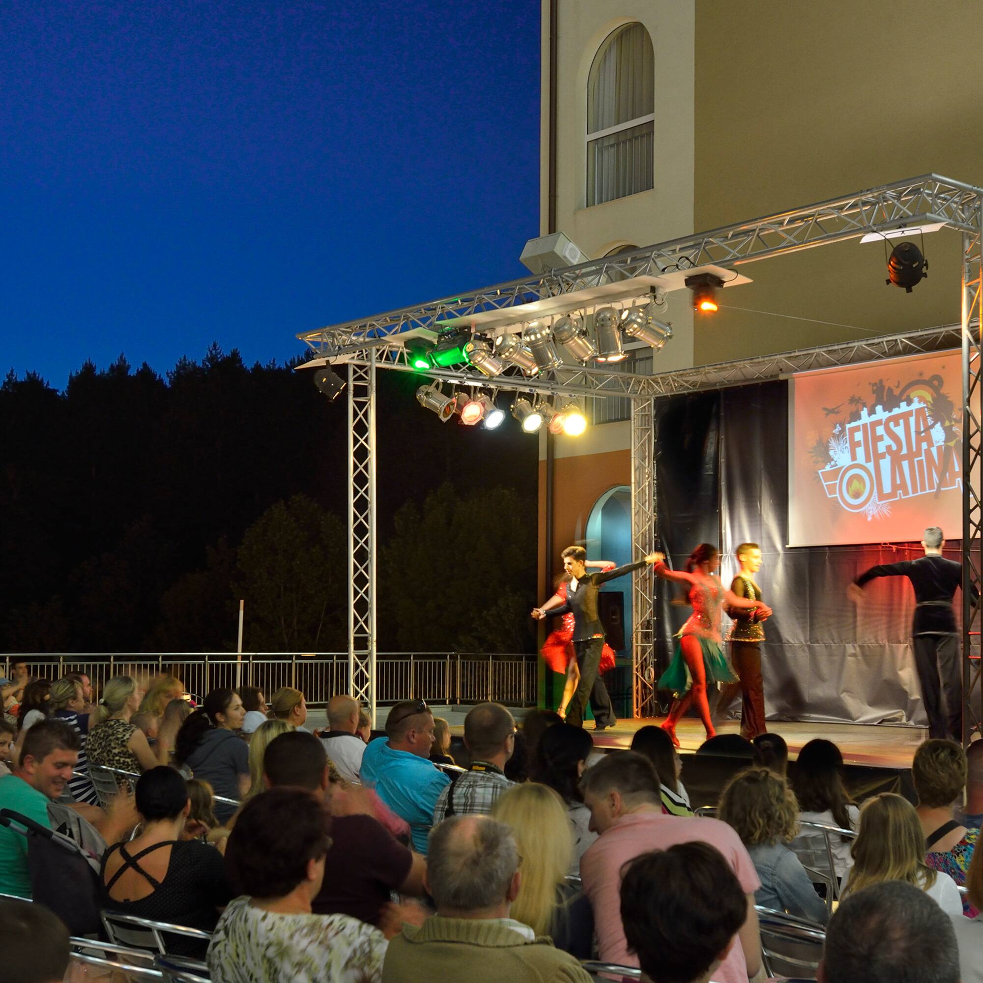 a group of people performing on a stage with a crowd watching