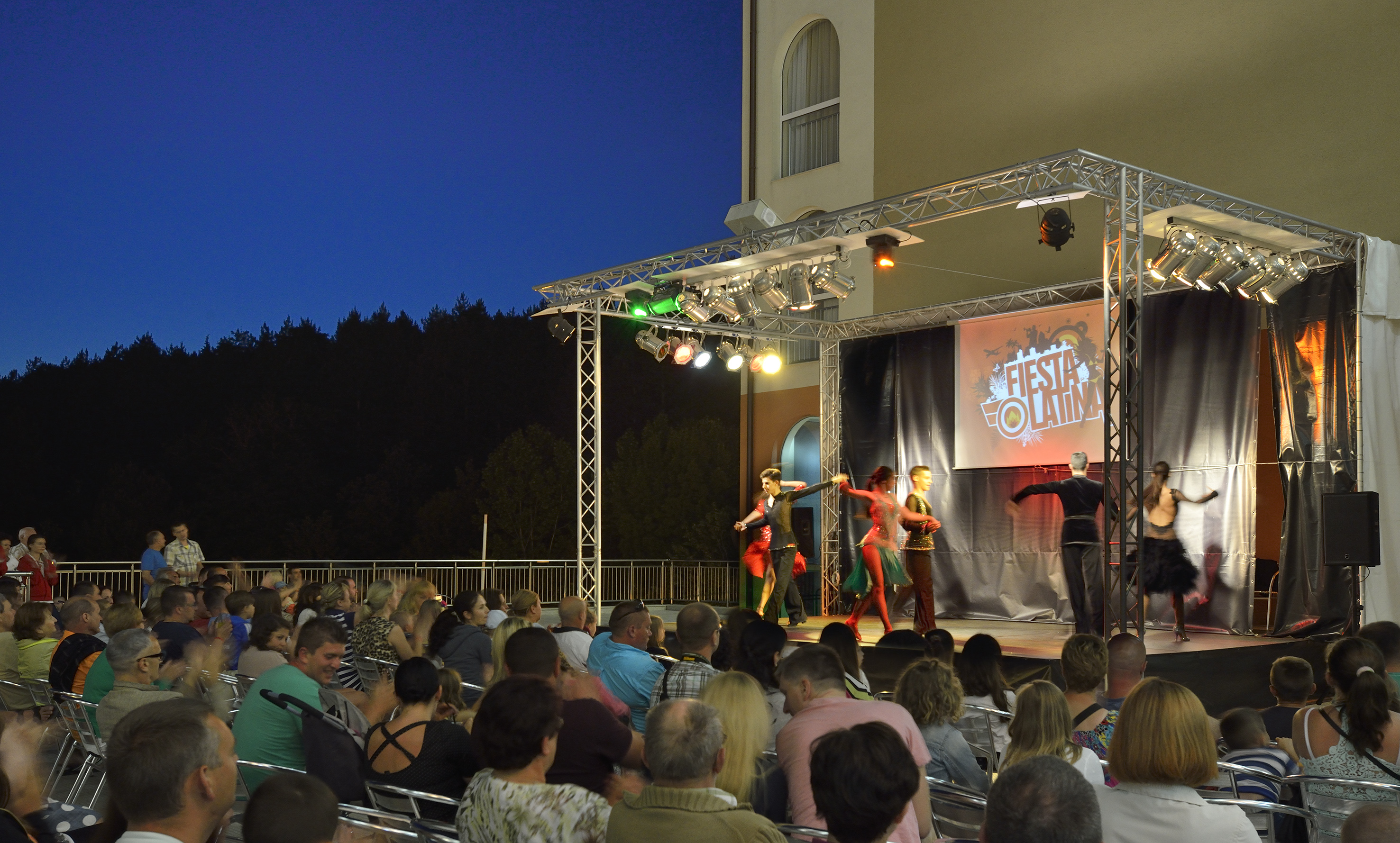 a group of people performing on a stage with a crowd watching