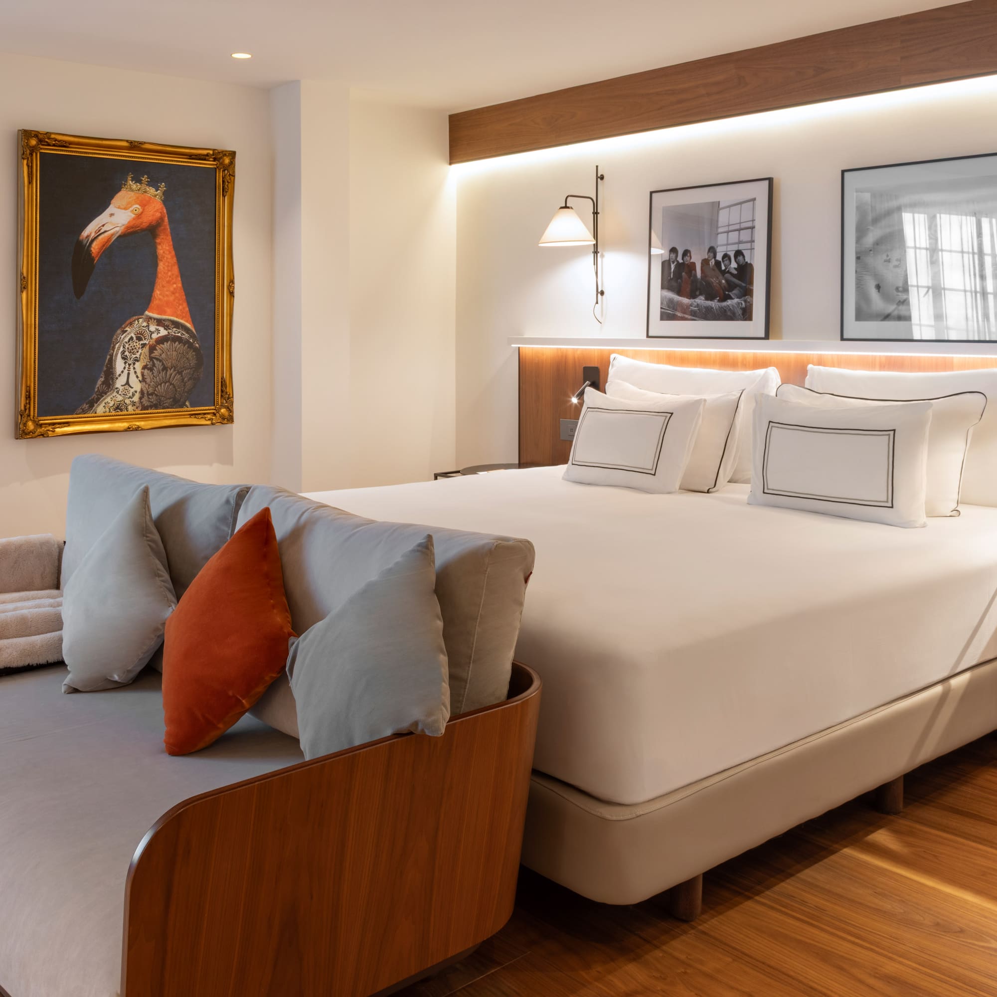 Modern hotel bedroom with large bed, gray sofa, and eclectic animal wall art.