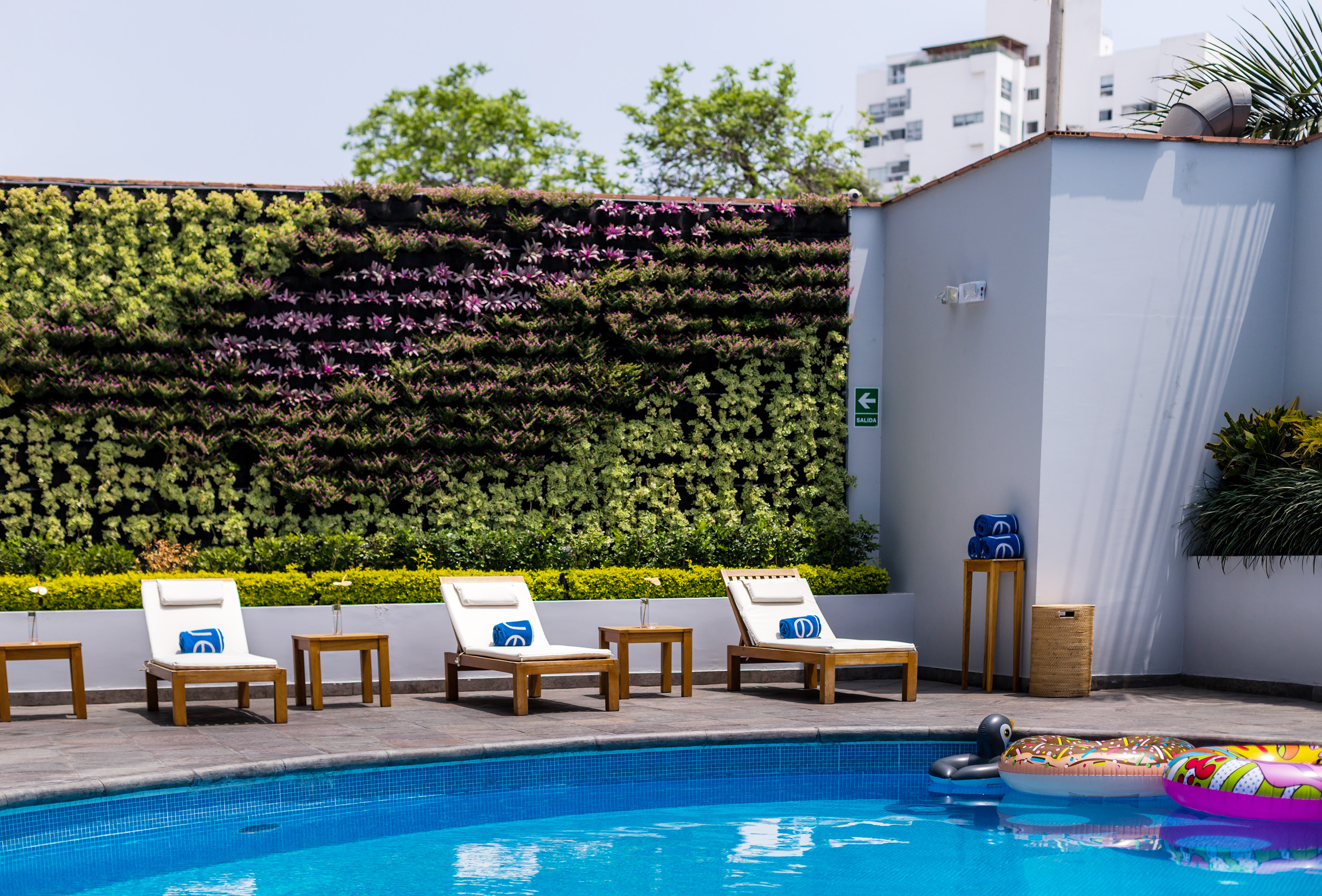 Hotel swimming pool with lounge chairs and a vibrant green living wall.