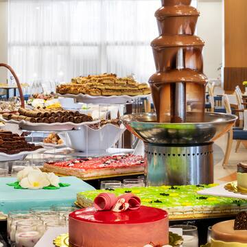 a chocolate fountain on a table with many different cakes