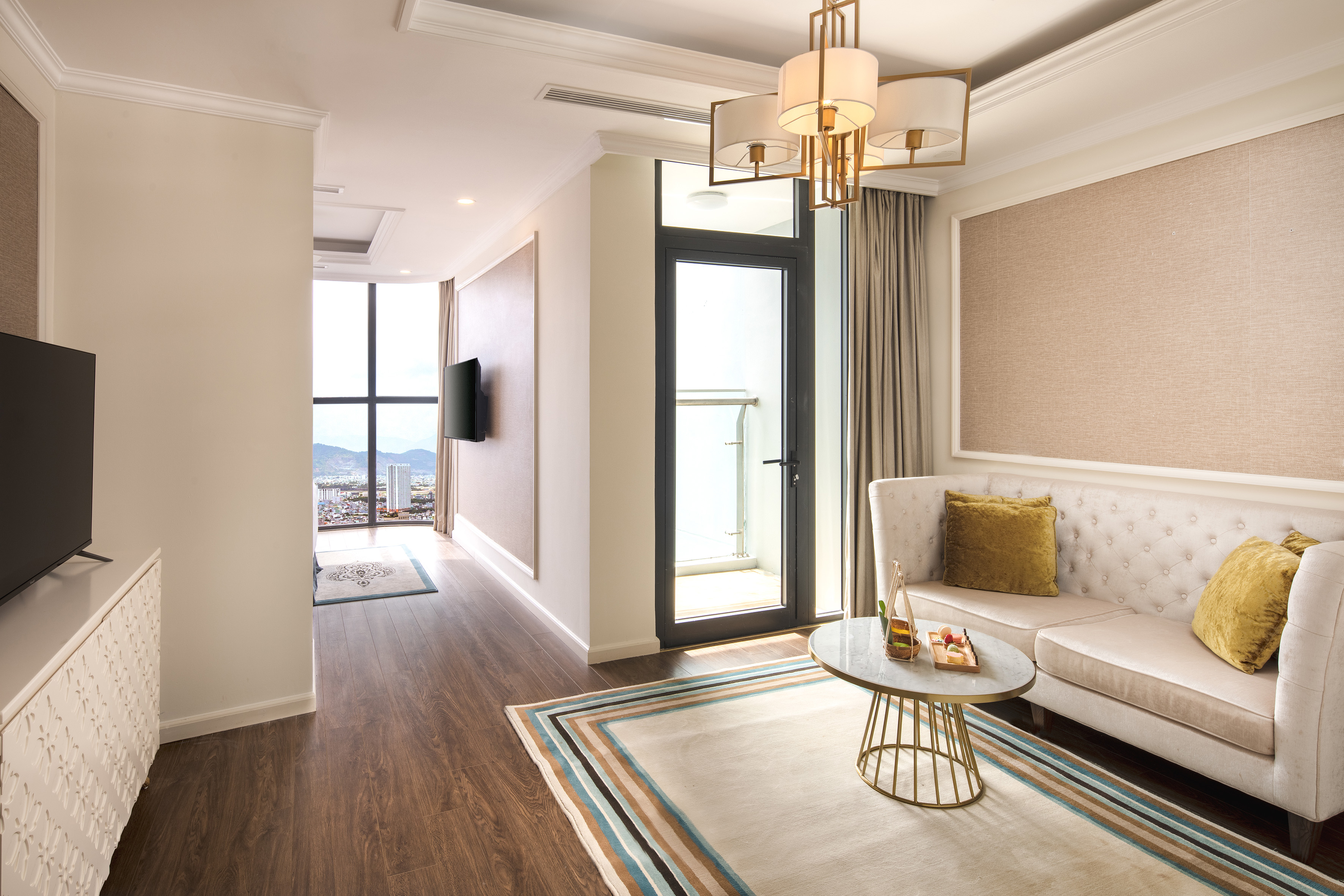 Luxury hotel living room with city view, sofa, modern decor, and balcony.
