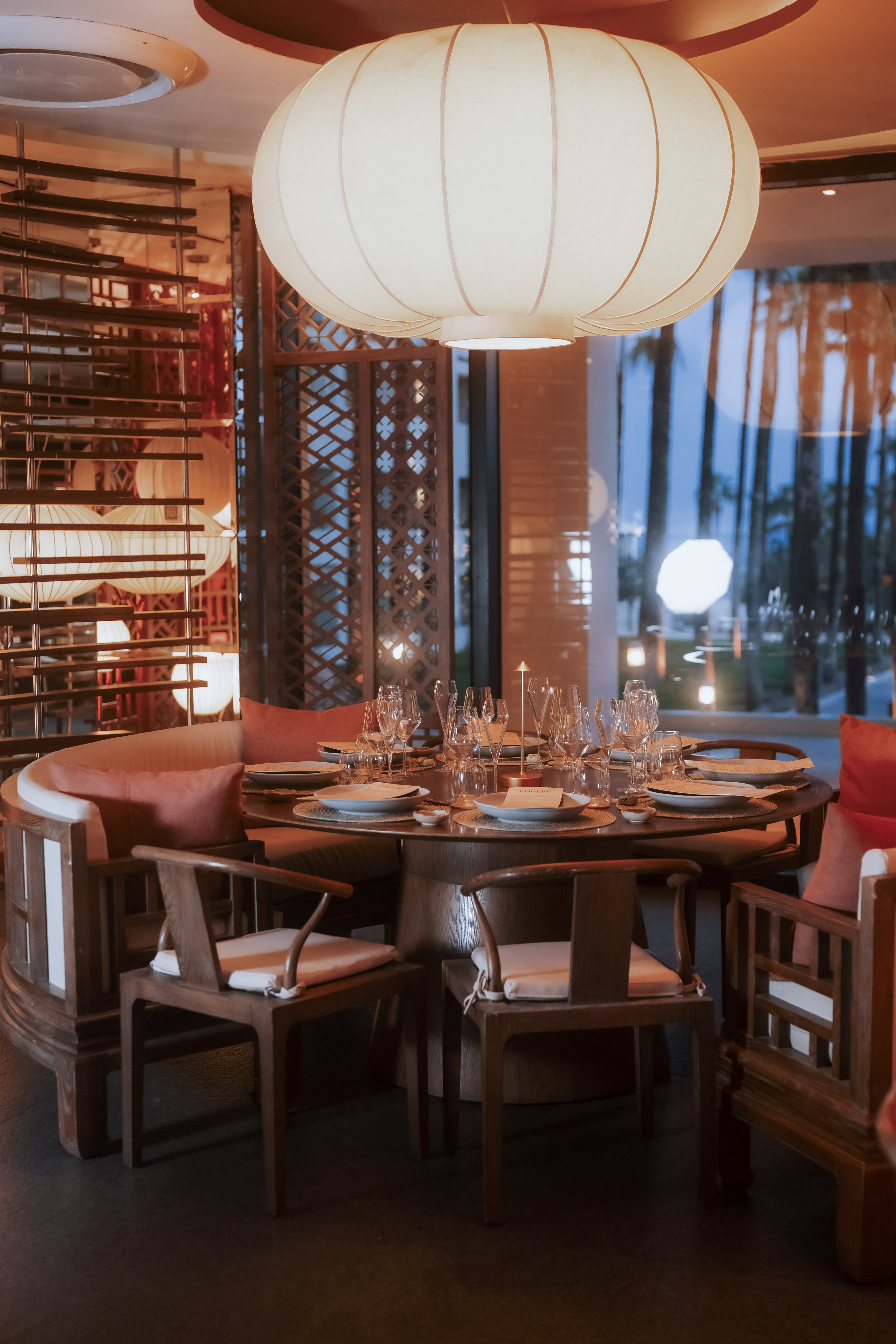 Elegant Asian restaurant interior with round dining table, lantern, and outdoor view.