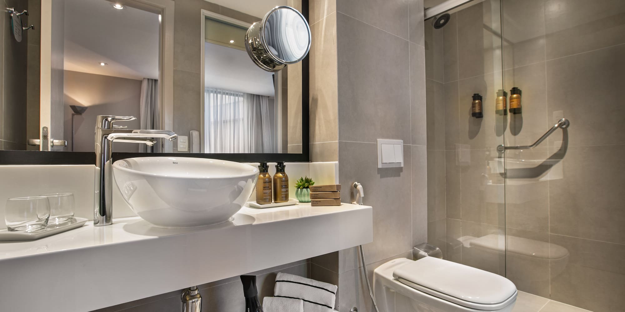 Modern hotel bathroom with vessel sink, accessible shower, and toilet.