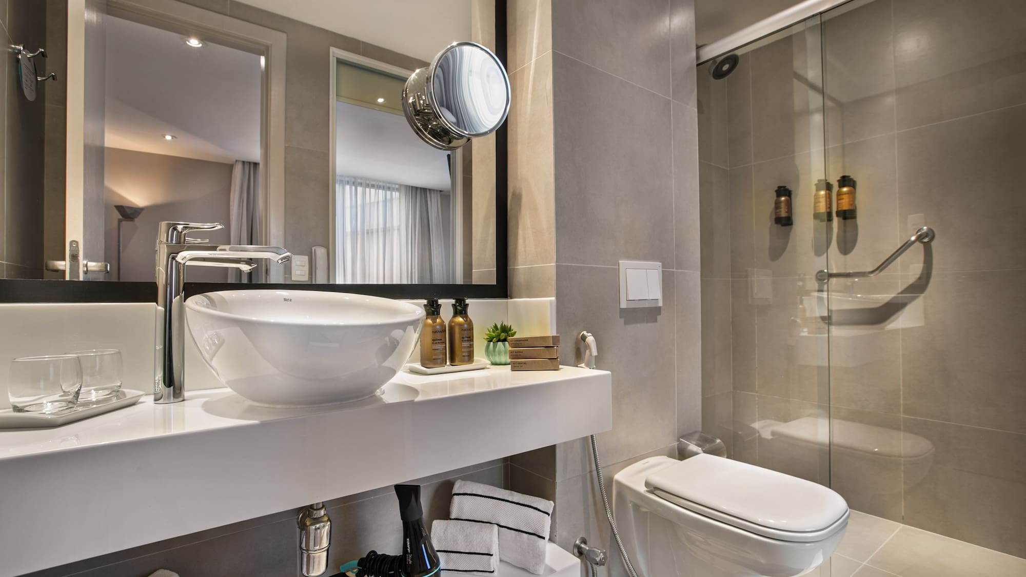 Modern hotel bathroom with vessel sink, accessible shower, and toilet.