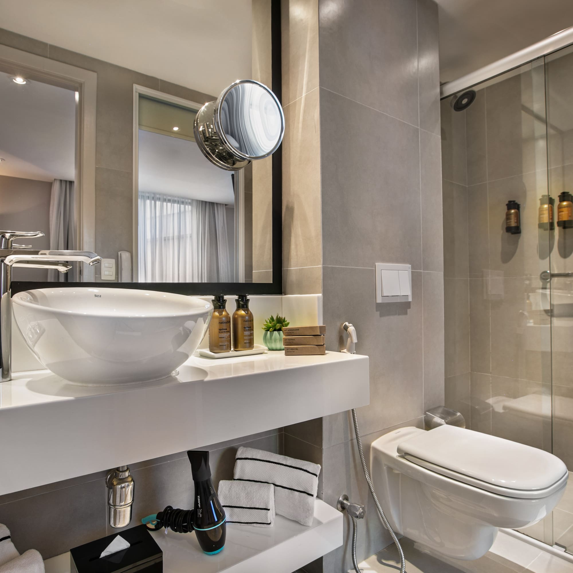 Modern hotel bathroom with vessel sink, accessible shower, and toilet.