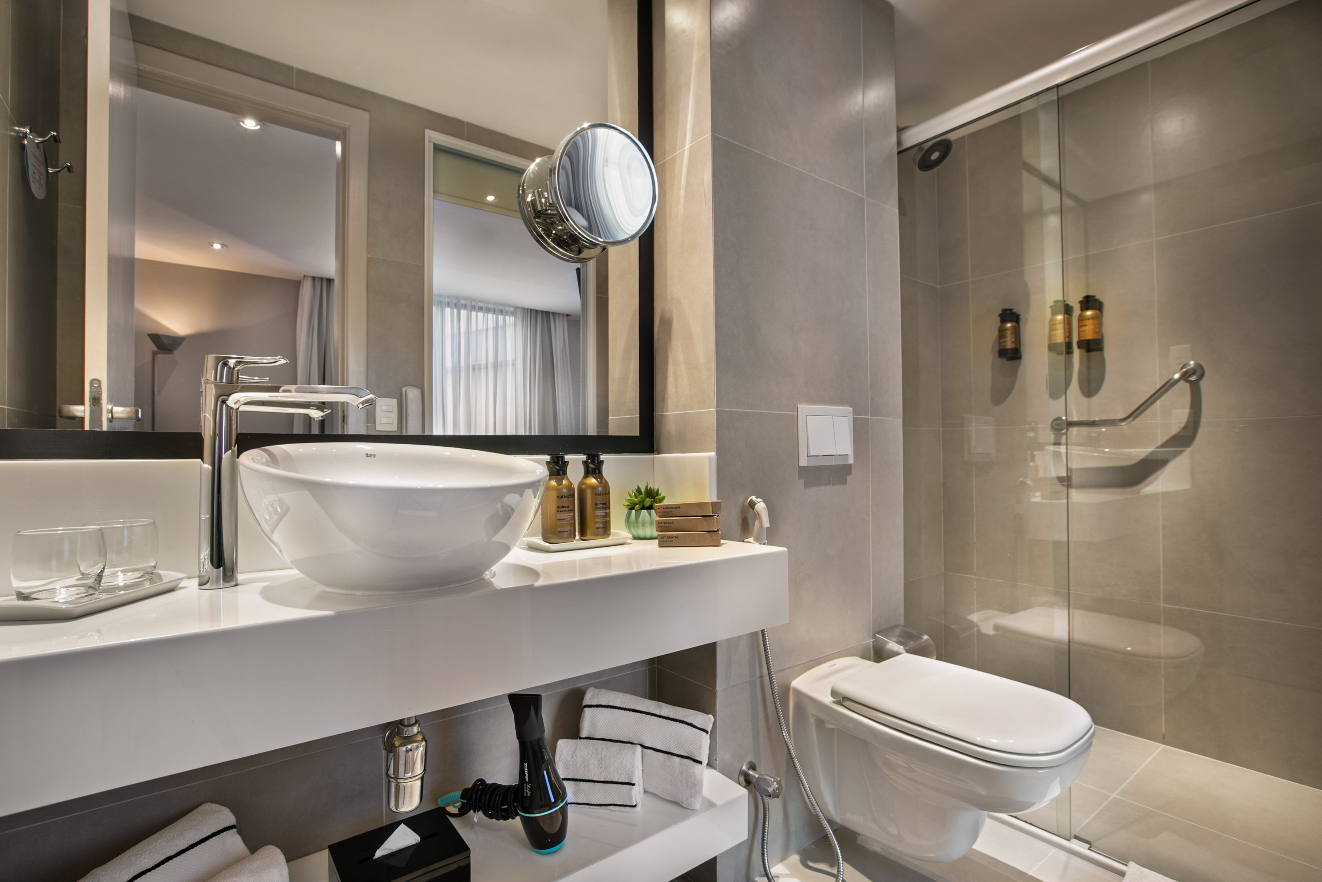 Modern hotel bathroom with vessel sink, accessible shower, and toilet.