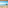 Beach resort balcony view: blue ocean, sandy beach, palm trees, island.